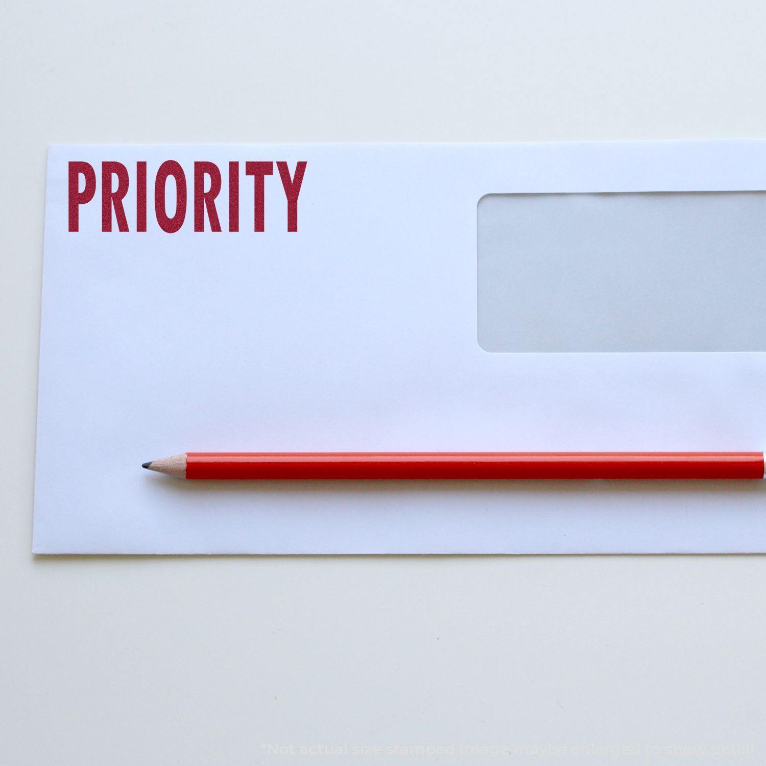 Large Pre-Inked Priority Stamp used on a white envelope with a red pencil placed diagonally across the envelope.