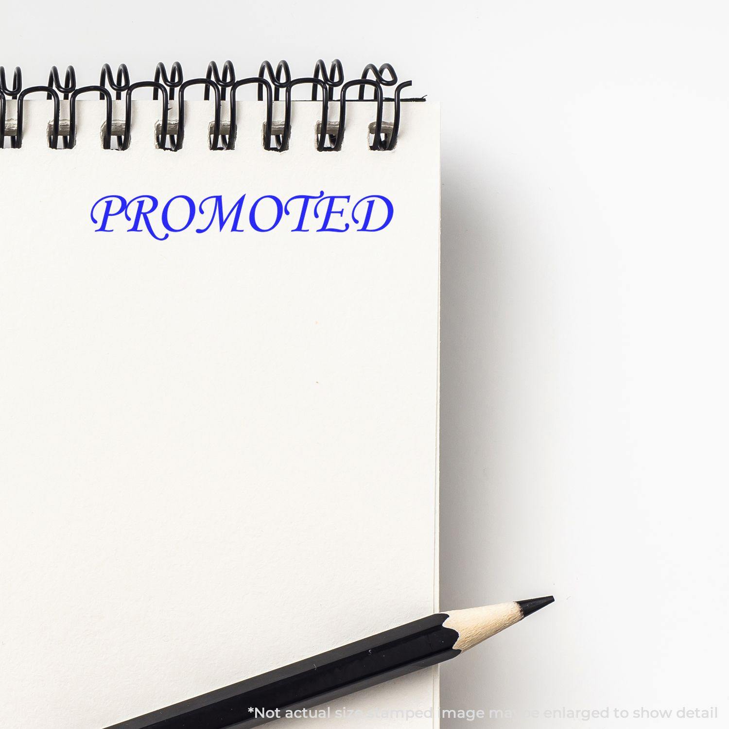 Large Pre-Inked Promoted Stamp imprinting PROMOTED in blue ink on a white notepad, with a black pencil placed beside it.