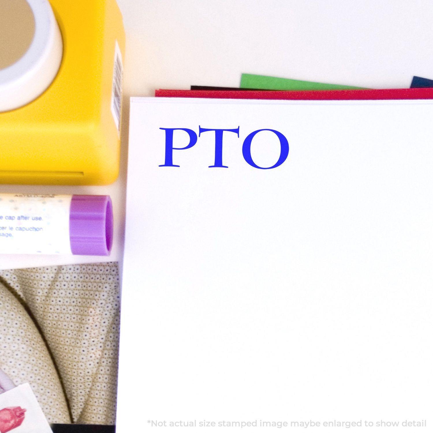 PTO rubber stamp impression on white paper with a yellow stamp pad and other office supplies in the background.