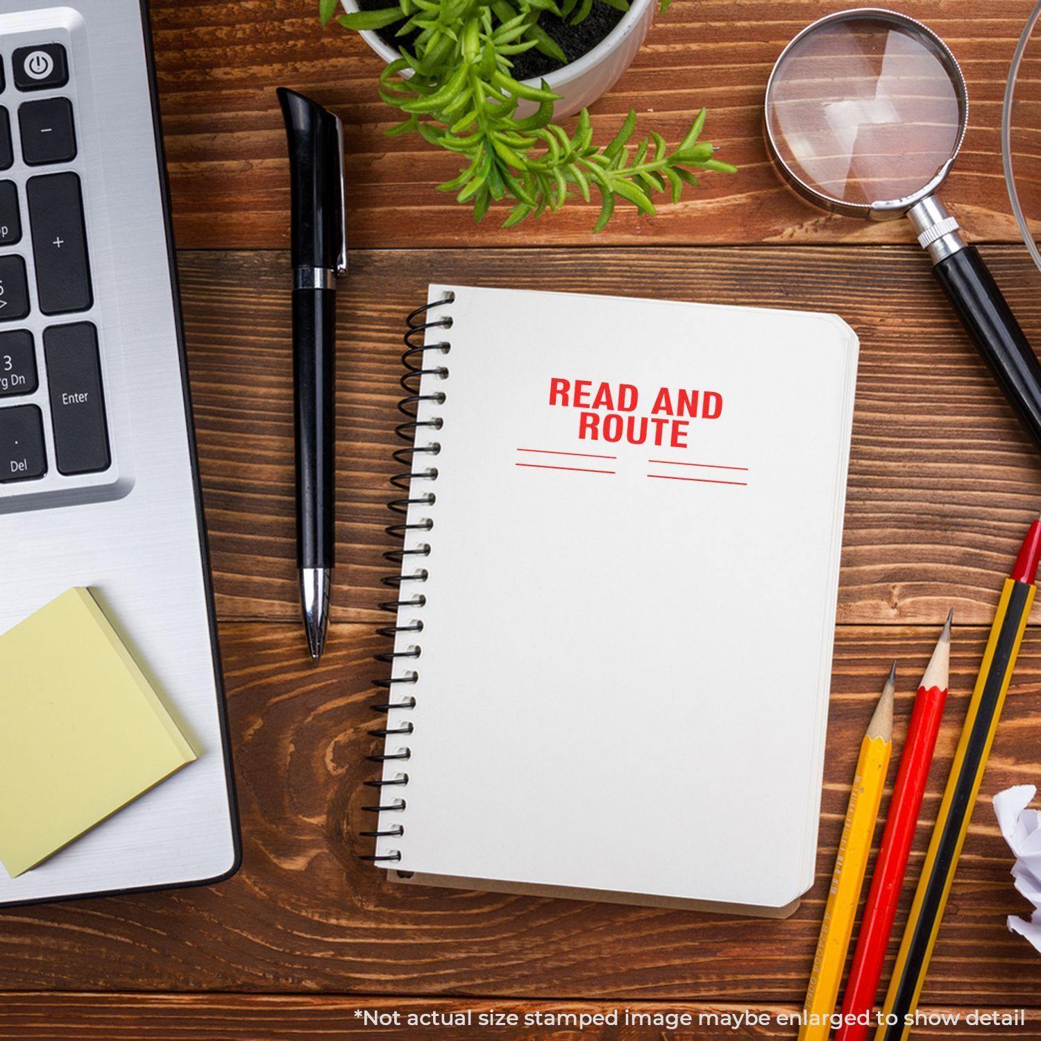 Notebook stamped with Read and Route using the Large Read and Route with Lines Rubber Stamp, surrounded by office supplies on a wooden desk.