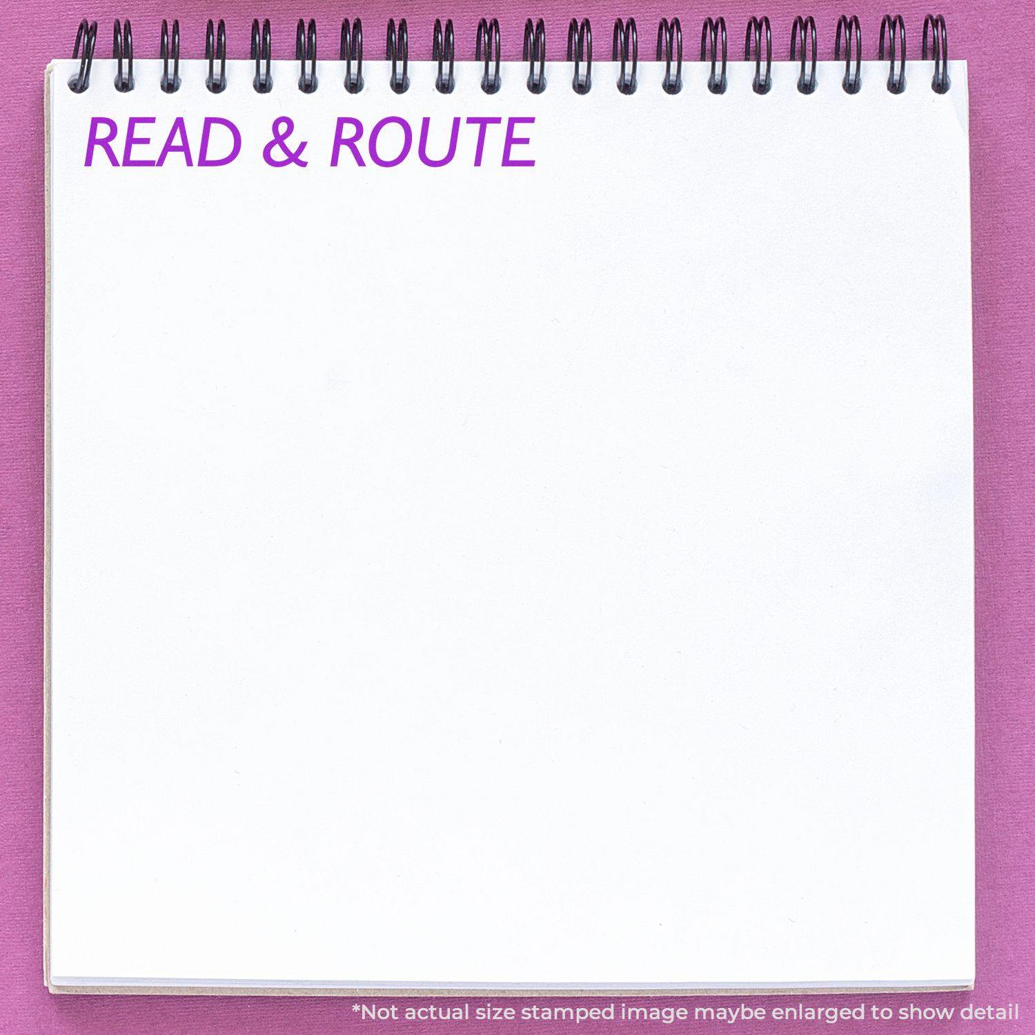 Large Pre-Inked Read & Route Stamp used on a white spiral notebook with READ & ROUTE stamped in purple on a pink background.