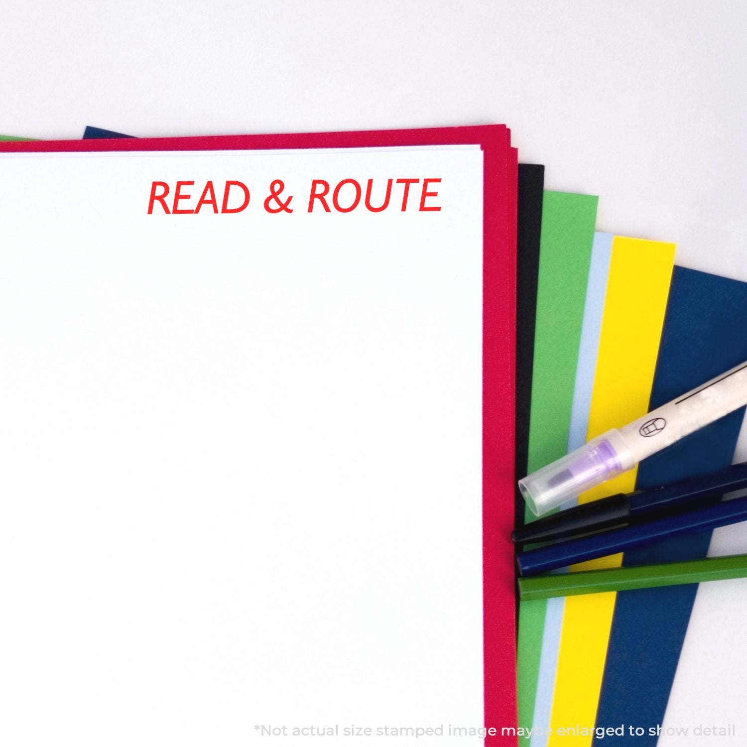 Self Inking Read Route Stamp in red ink on white paper, surrounded by colorful folders and pens.