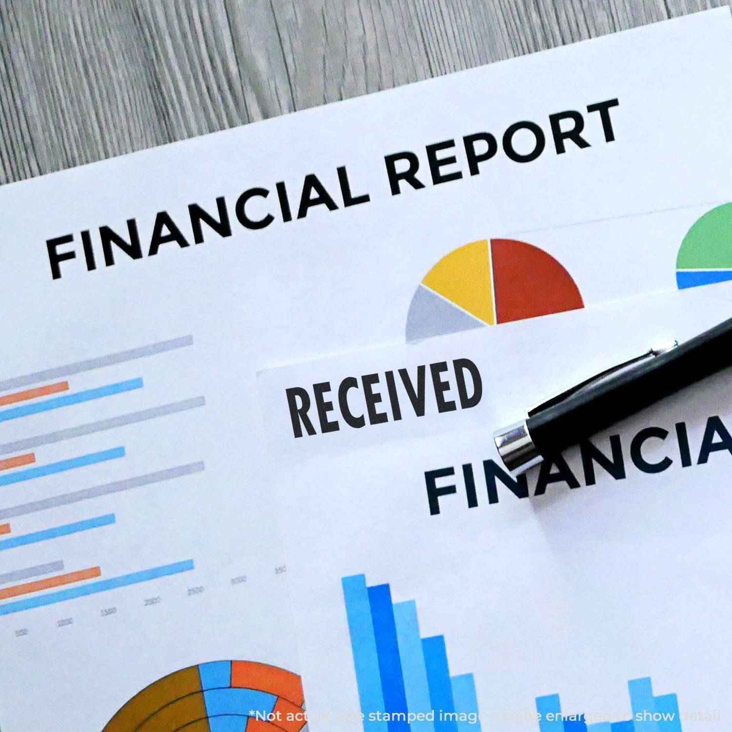 Financial reports with charts and graphs, one stamped with RECEIVED using a Large Received Rubber Stamp, and a pen placed on top.