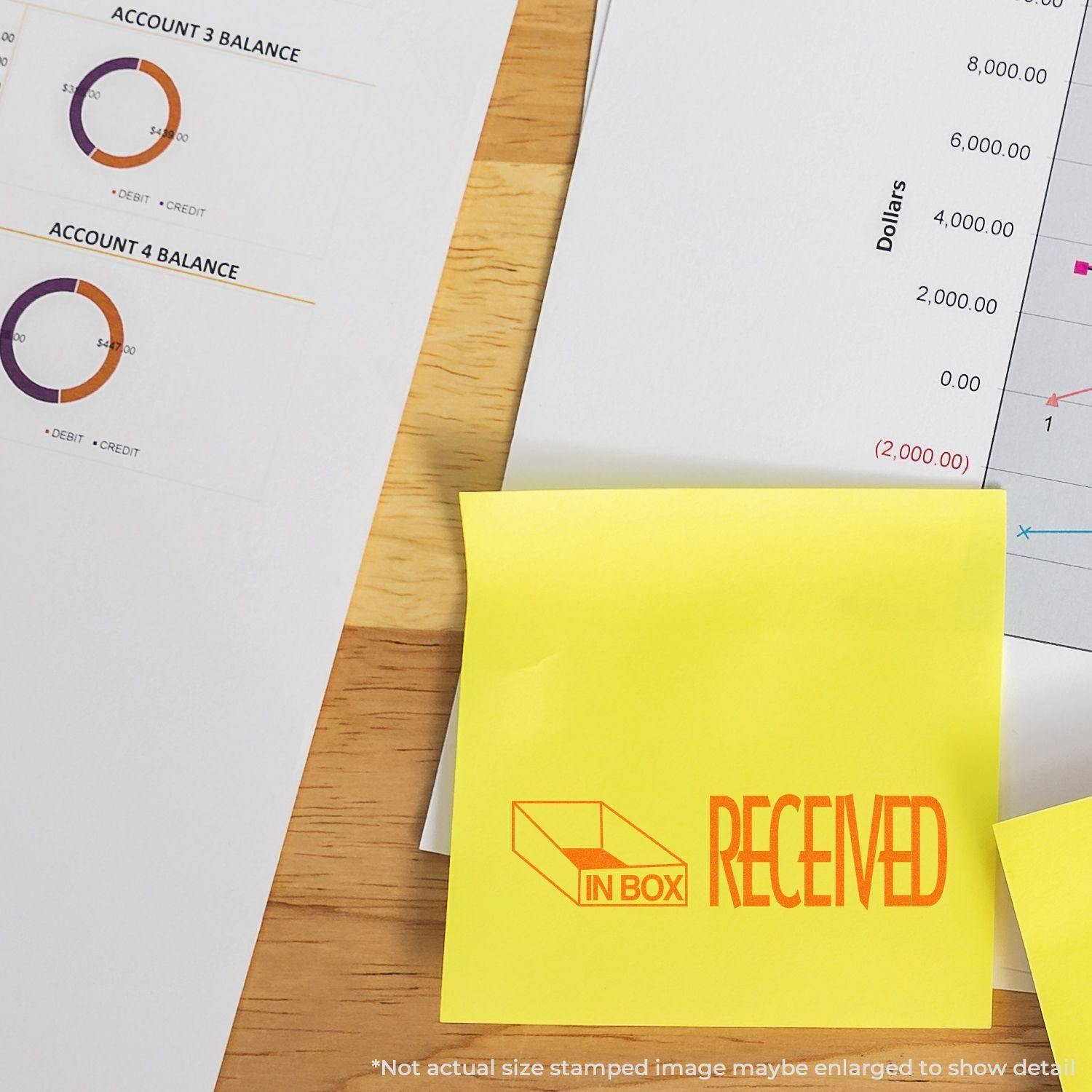 Large Received with Inbox Icon Rubber Stamp used on a yellow sticky note, placed on a desk with financial documents and charts.