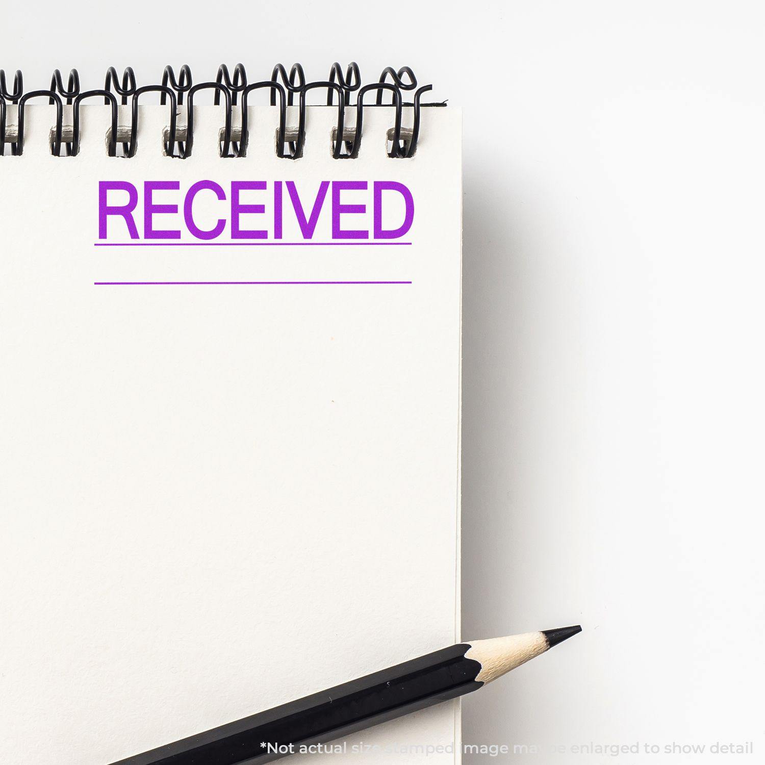 Large Self Inking Received with Line Stamp imprint in purple on a white notepad with a pencil beside it.