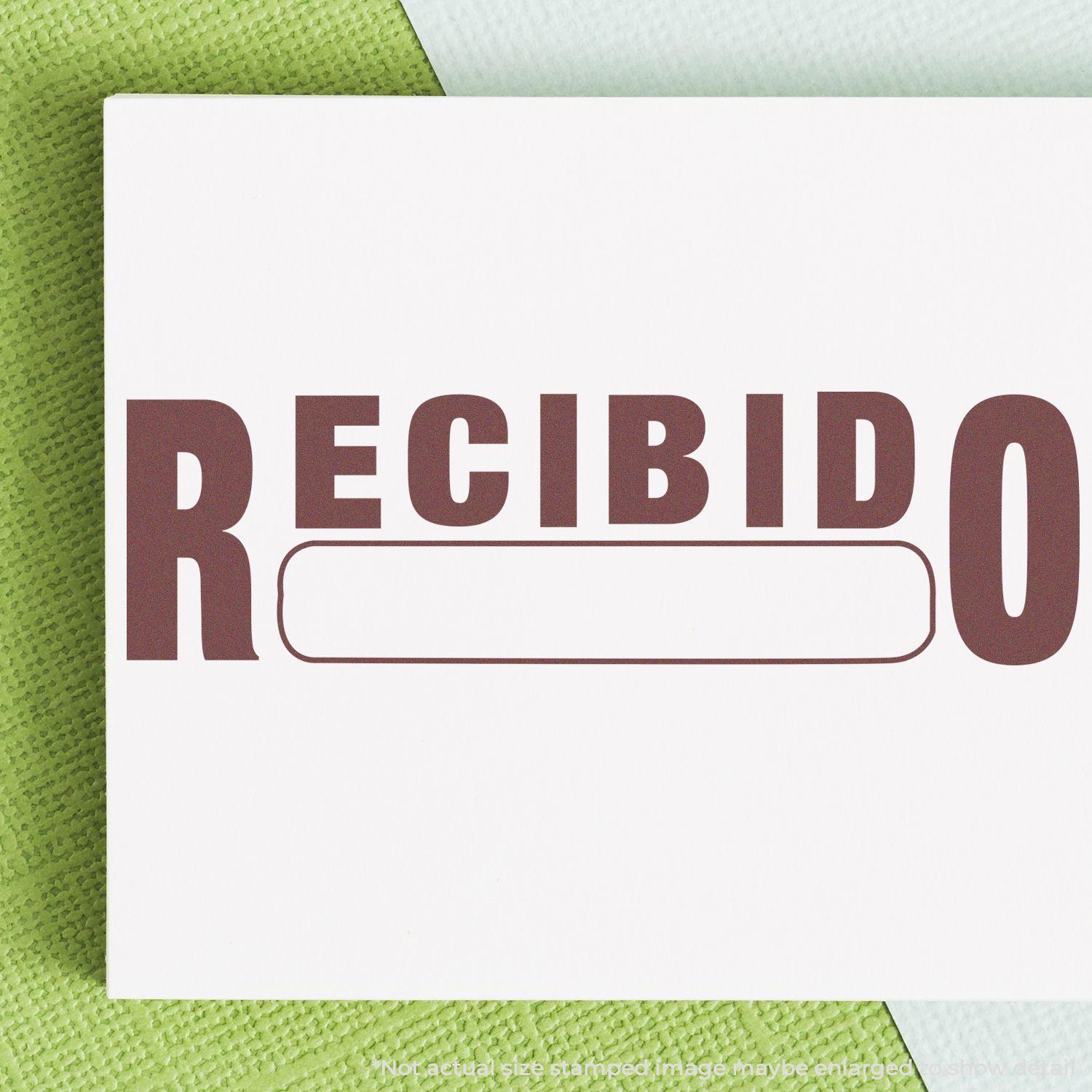 Large Pre-Inked Recibido Stamp in use, showing the word RECIBIDO stamped in bold letters on a white paper with a green background.