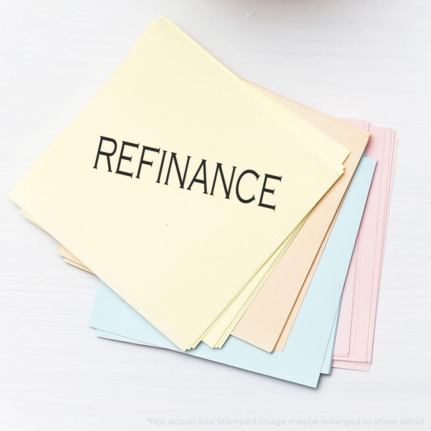 Large Self Inking Refinance Stamp used on a stack of pastel-colored papers with the word REFINANCE clearly stamped on top.