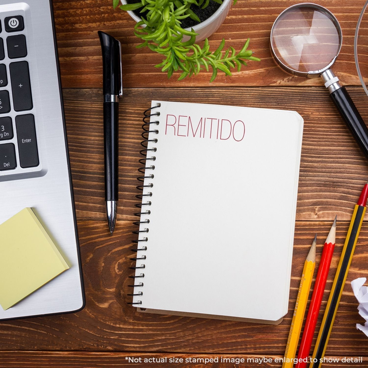 A Self Inking Remitido Stamp is used on a notebook page, surrounded by a laptop, pen, sticky notes, plant, magnifying glass, and pencils.