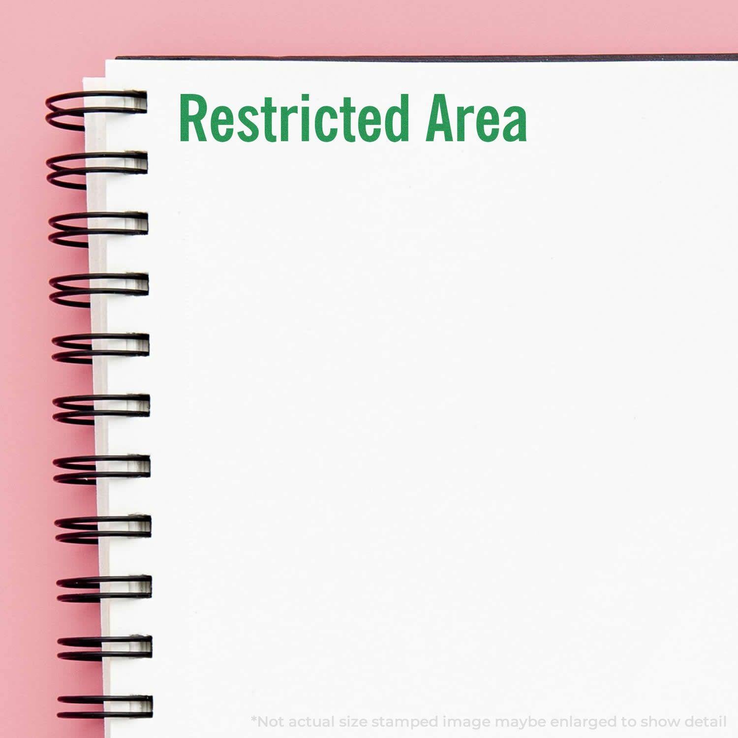 Large Pre-Inked Restricted Area Stamp used on a white spiral notebook, displaying Restricted Area in green text on a pink background.