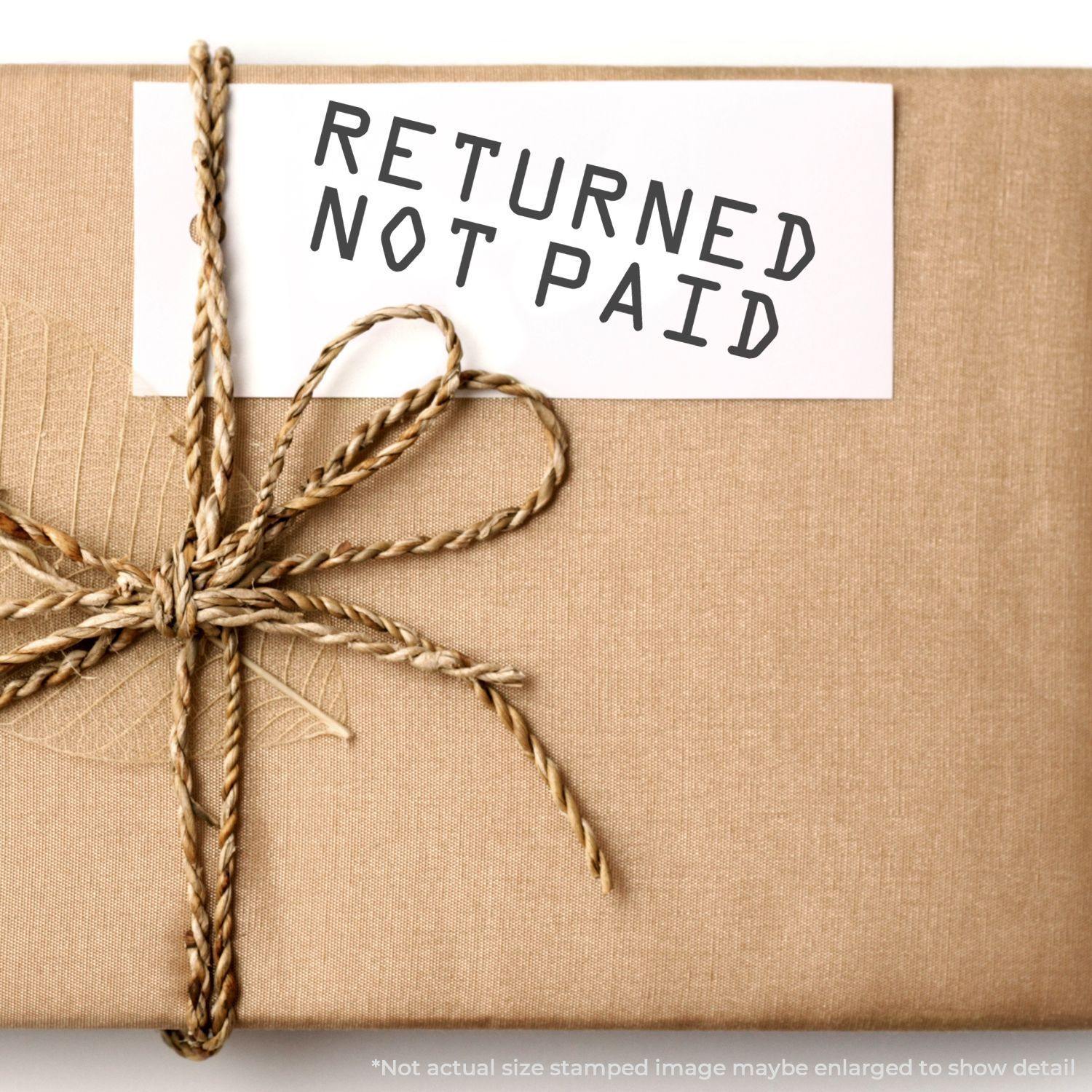 Slim Pre-Inked Returned Not Paid Stamp used on a white card attached to a wrapped brown package with twine bow.