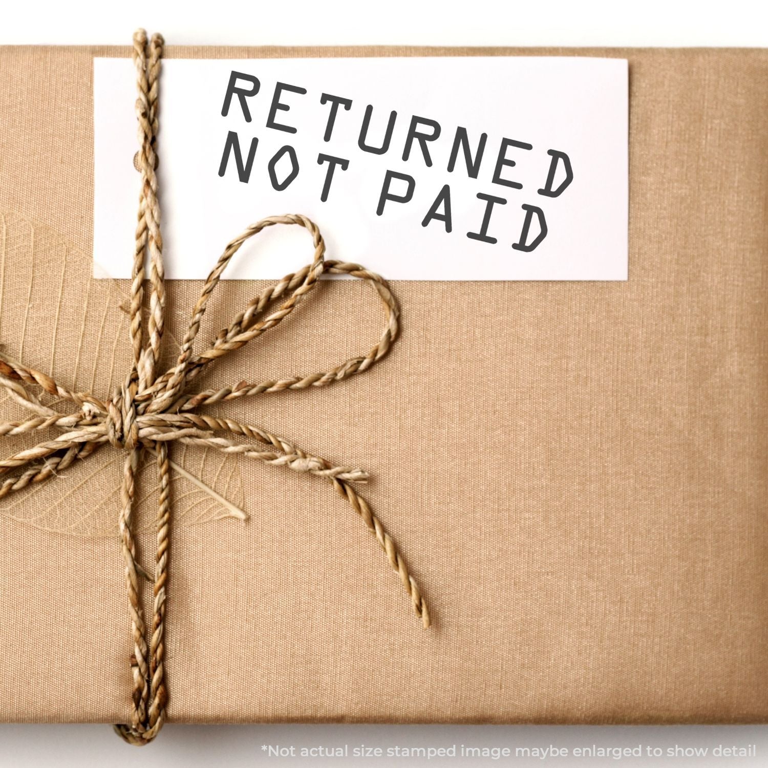 Self Inking Returned Not Paid Stamp used on a white card attached to a brown wrapped package with twine.