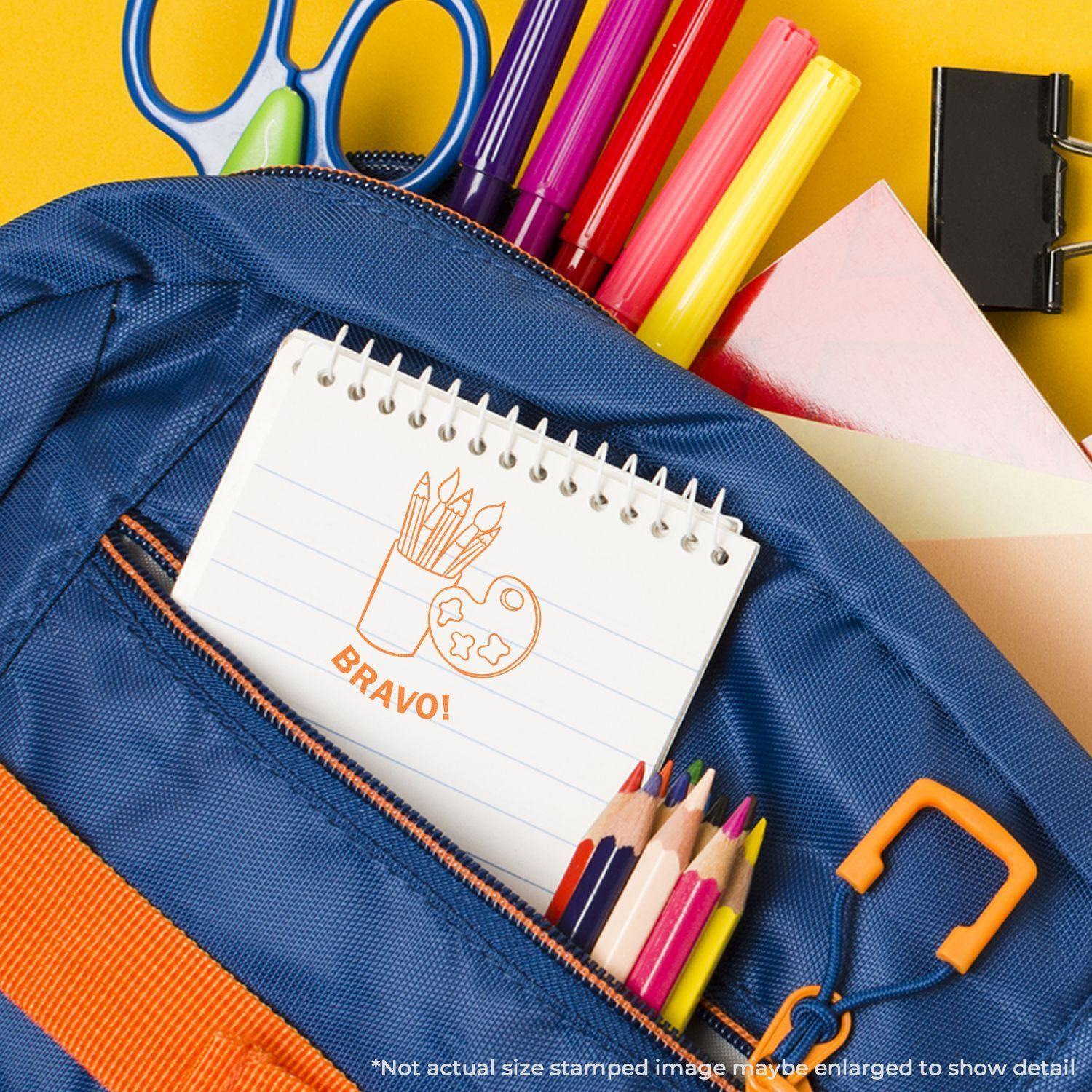 Round Bravo rubber stamp on a notepad in a blue backpack pocket, surrounded by colorful pens, pencils, and school supplies.