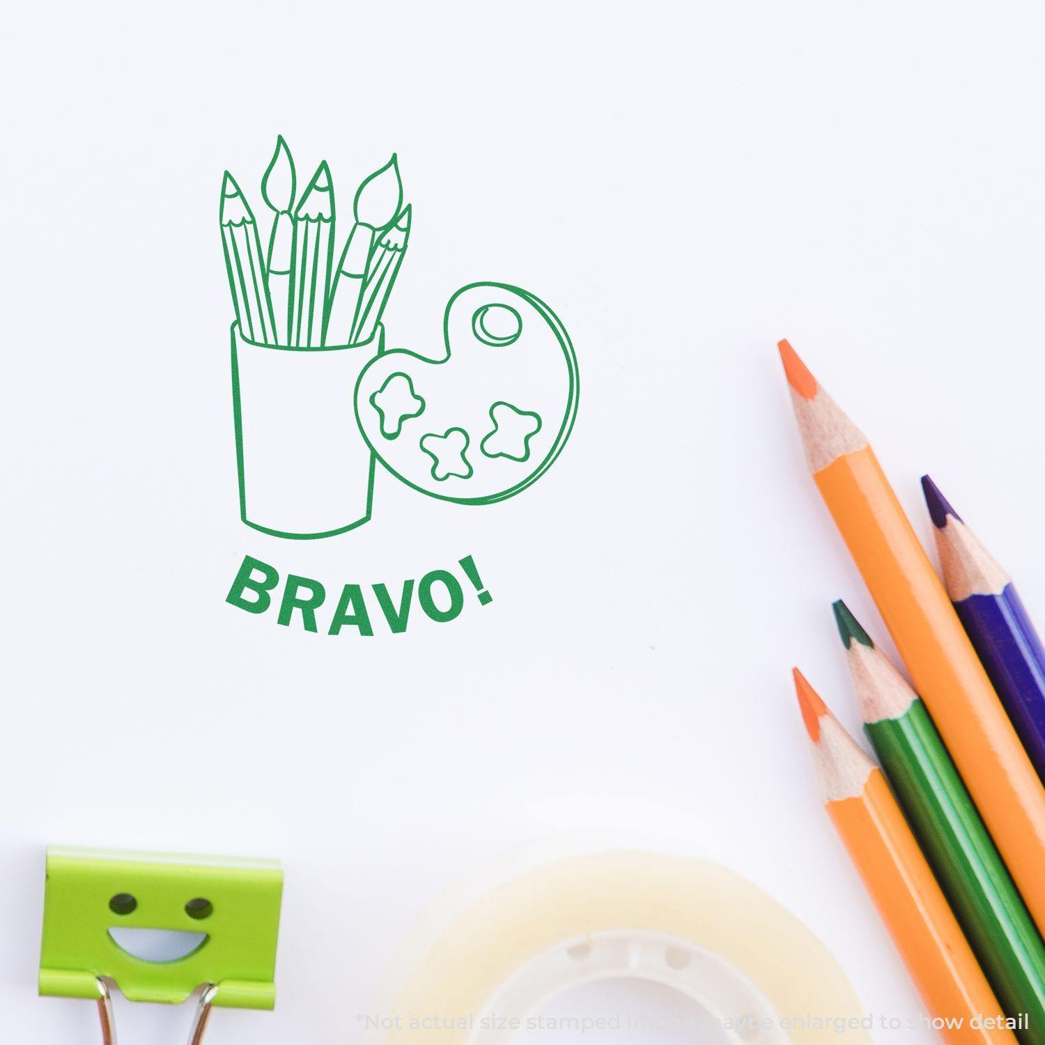 Round Bravo Rubber Stamp with a design of paintbrushes and a palette, stamped on paper near colored pencils and stationery.