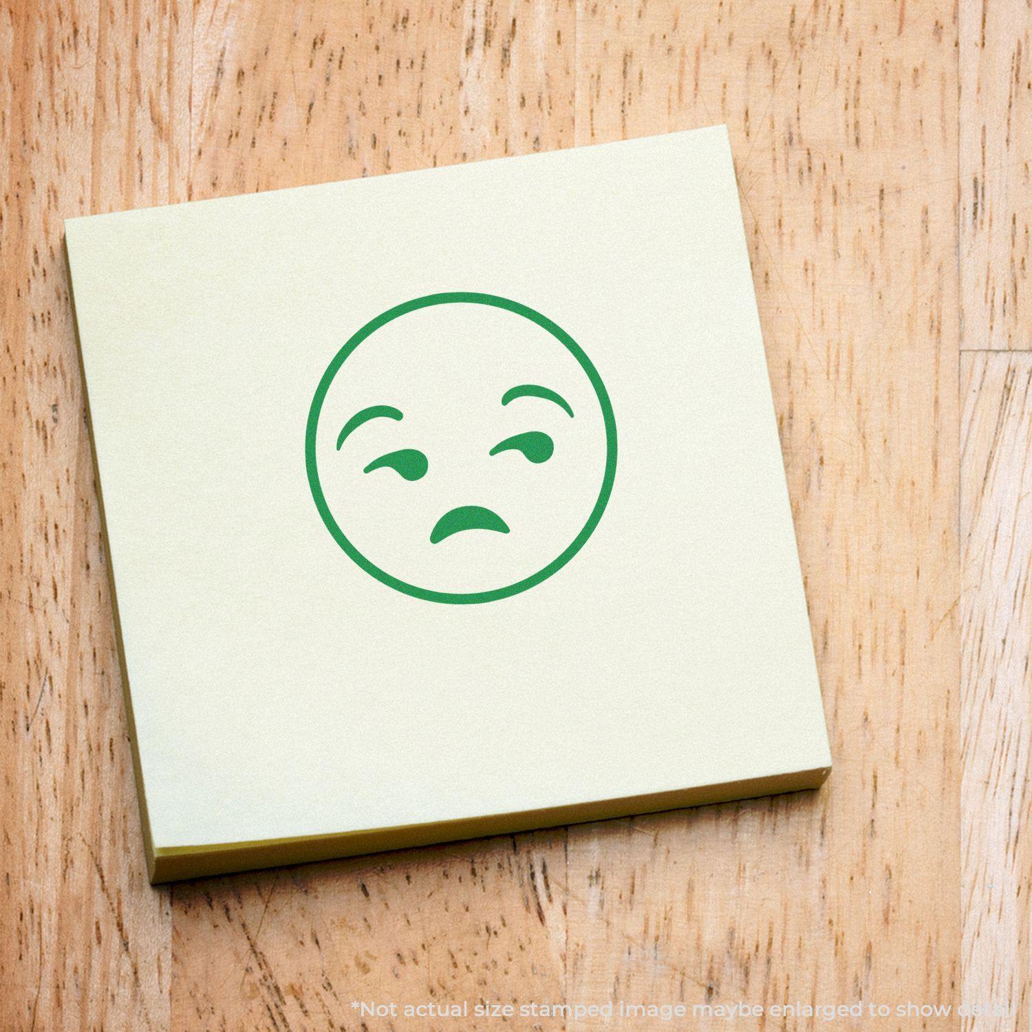 Round Calm Smiley Rubber Stamp impression on a yellow sticky note placed on a wooden surface.