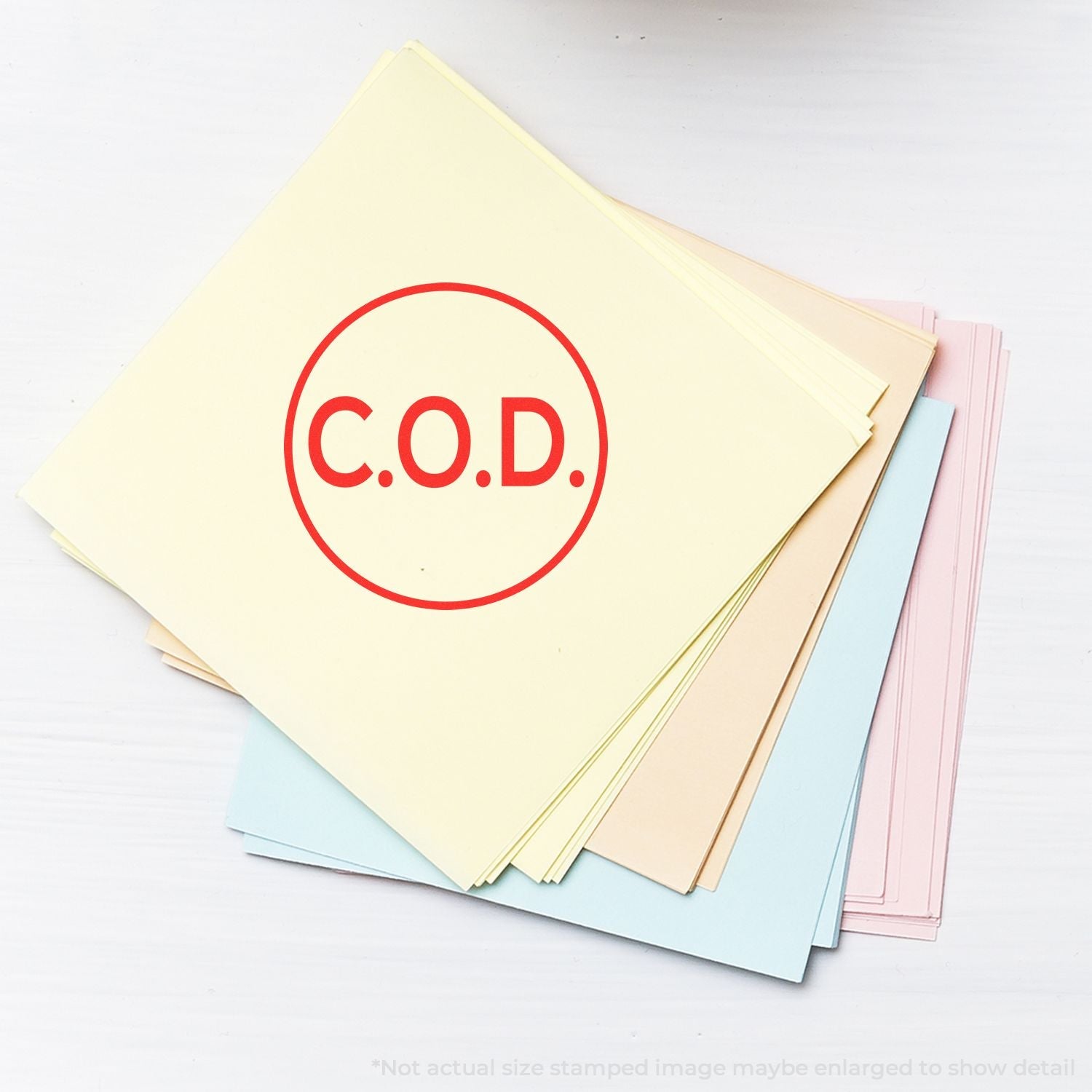 Self Inking Round COD Stamp marking C.O.D. in red on a stack of pastel-colored papers.