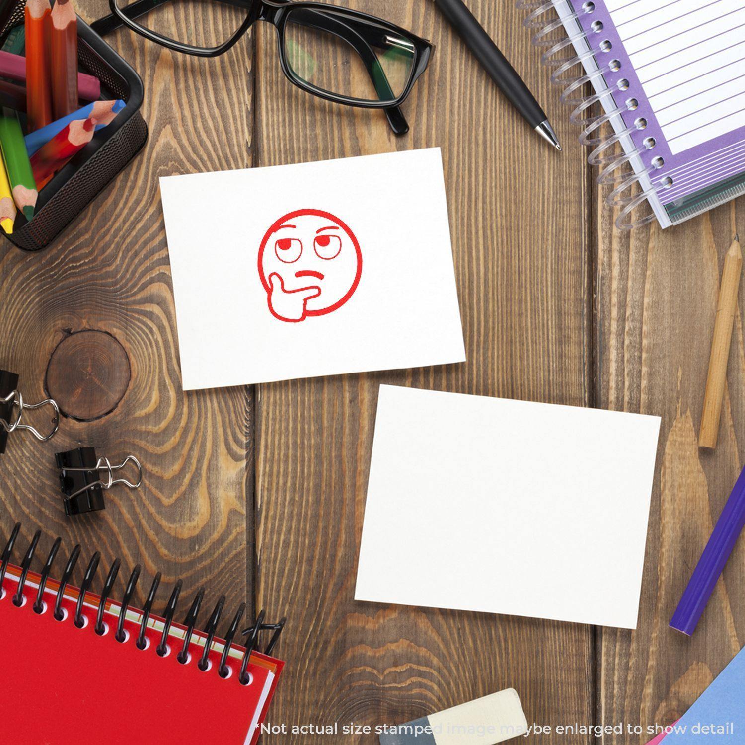 A desk with stationery items and two cards, one stamped with a red Round Curious Smiley Rubber Stamp, depicting a thinking face.