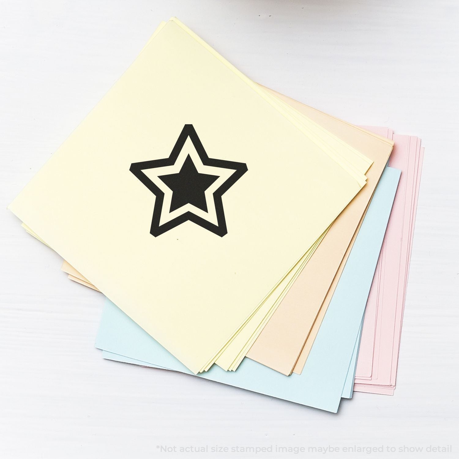 Self Inking Round Double Star Stamp used on a stack of pastel-colored papers, displaying a bold black double star imprint.