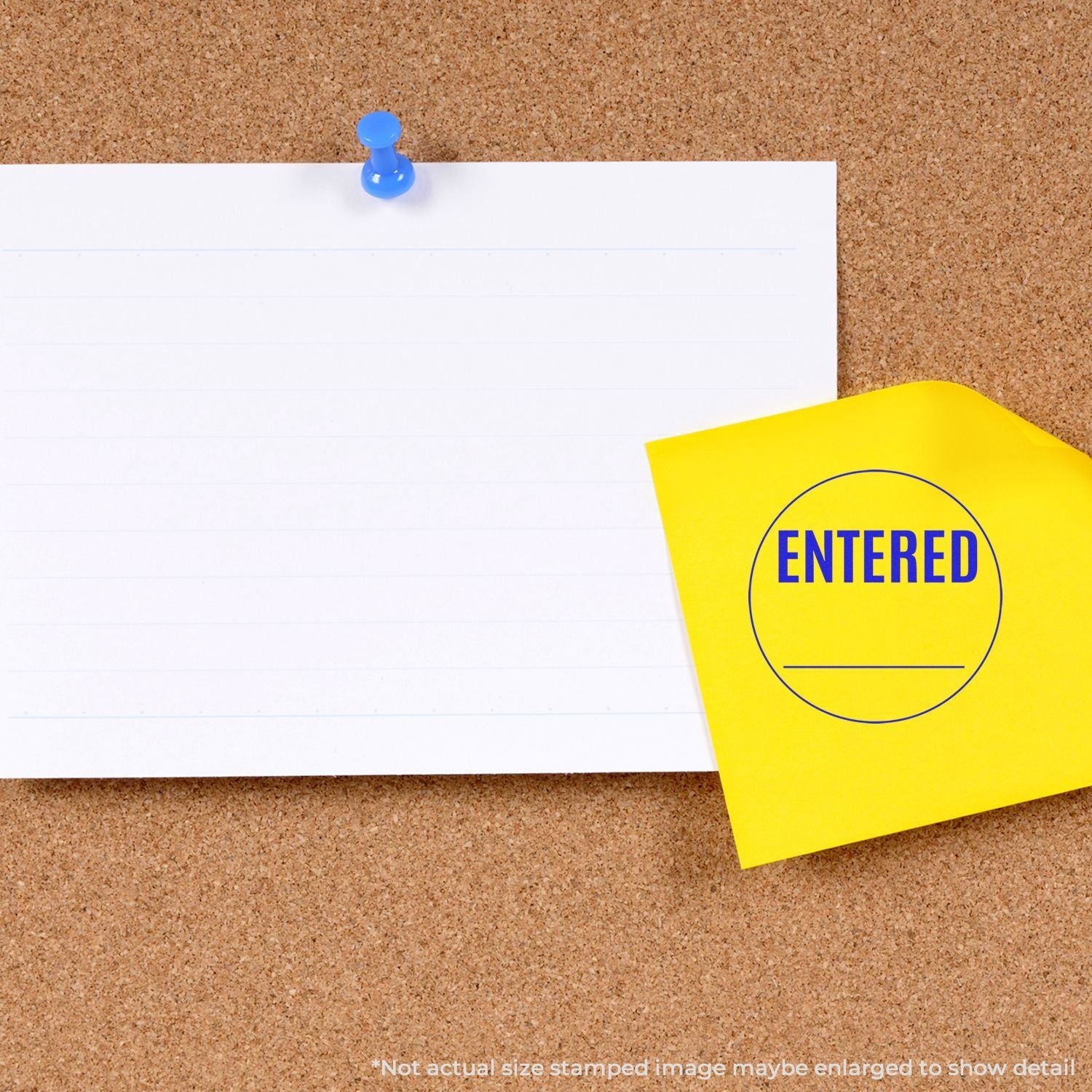 Self Inking Round Entered Stamp in blue ink on a yellow sticky note pinned to a corkboard next to a blank white paper.