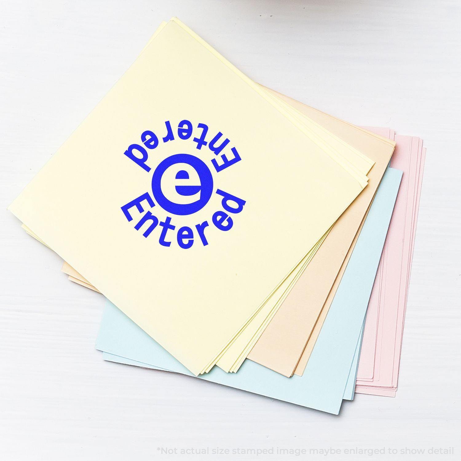 A stack of pastel-colored papers with a blue round Entered Entered rubber stamp impression on the top sheet.