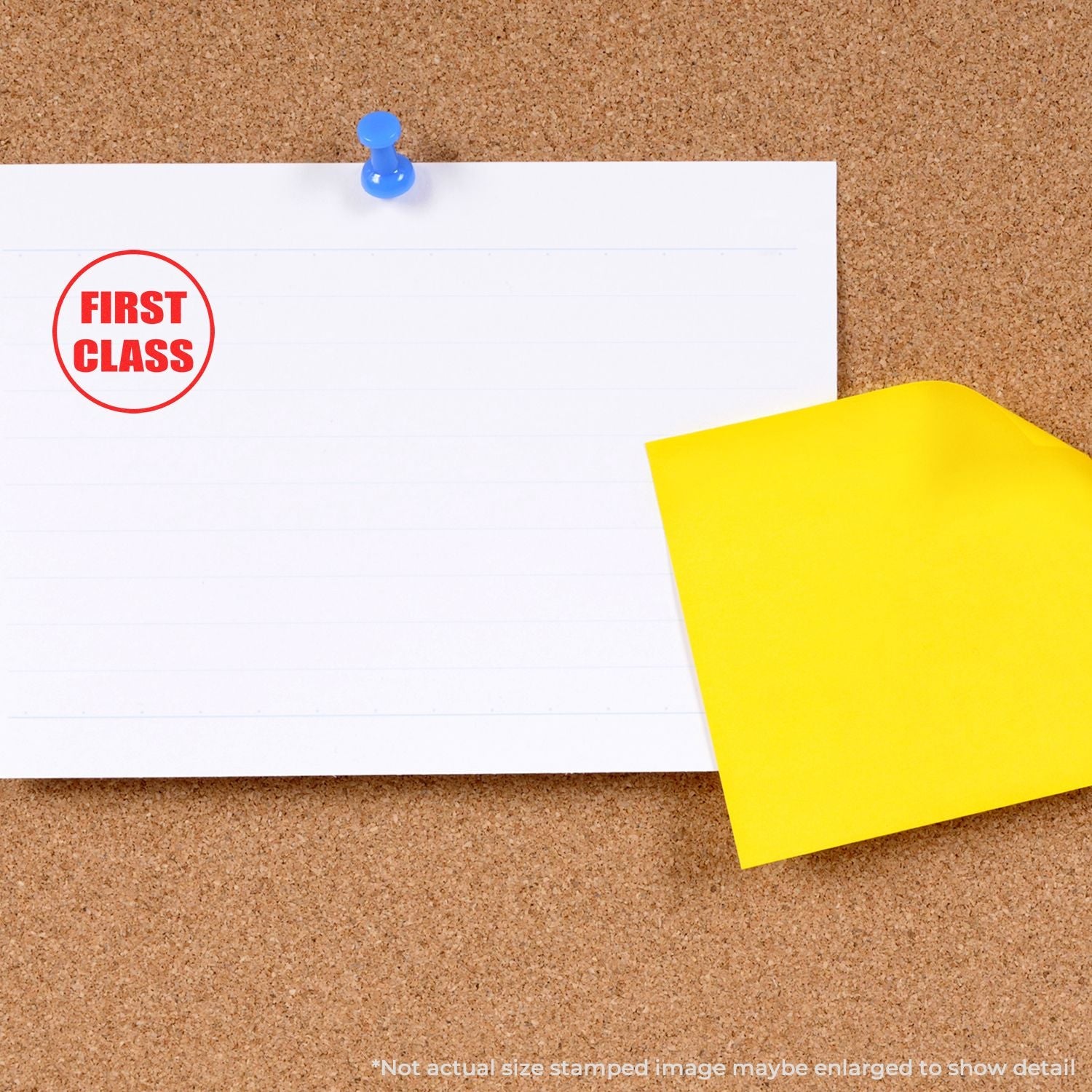 A corkboard with a white note stamped FIRST CLASS using a Self Inking Round First Class Stamp, pinned with a blue pushpin and a yellow sticky note.