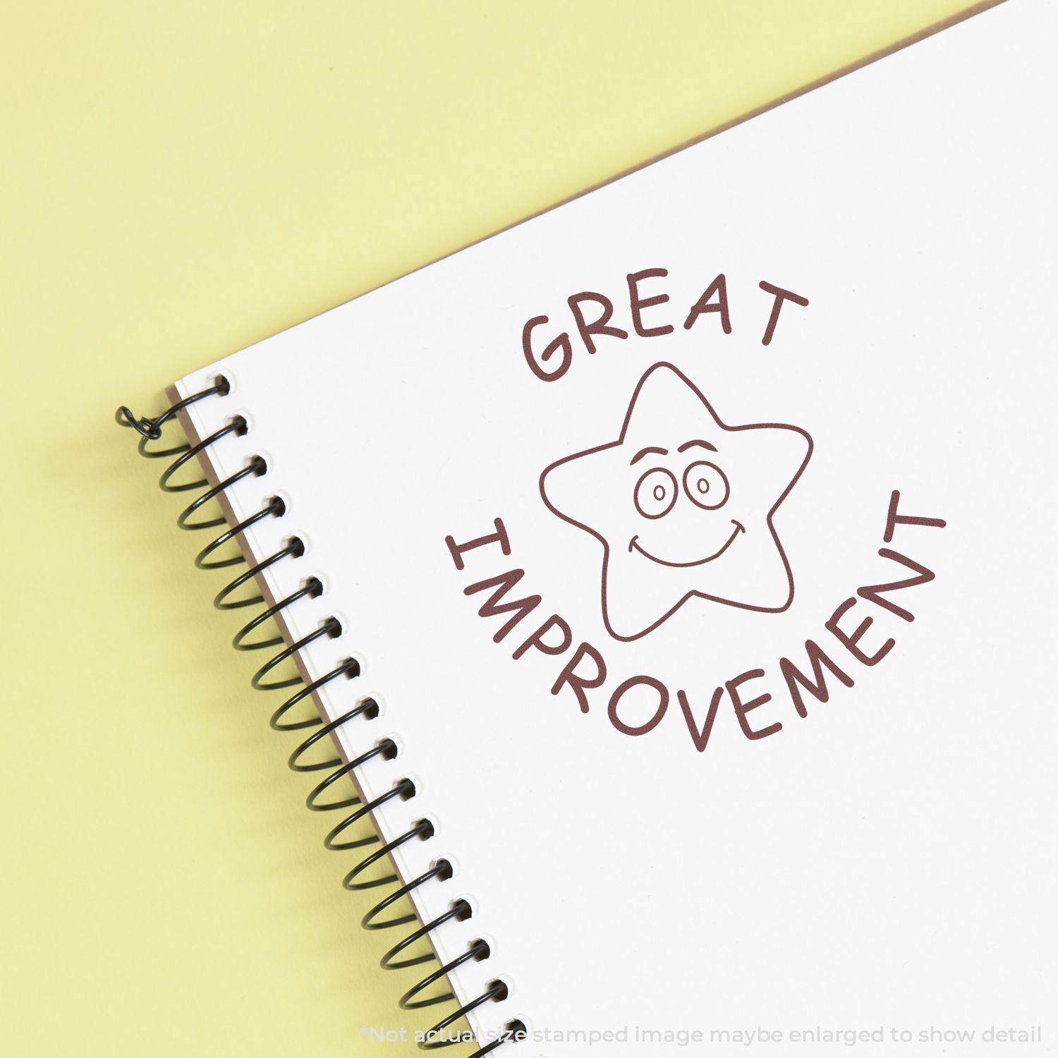 Round Great Improvement rubber stamp with a smiling star design stamped on a spiral notebook page.