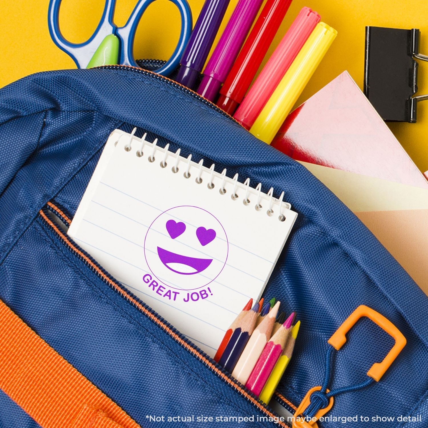 A notebook stamped with Self Inking Round Great Job Smiley Stamp in a blue backpack with colored pencils, markers, and scissors.