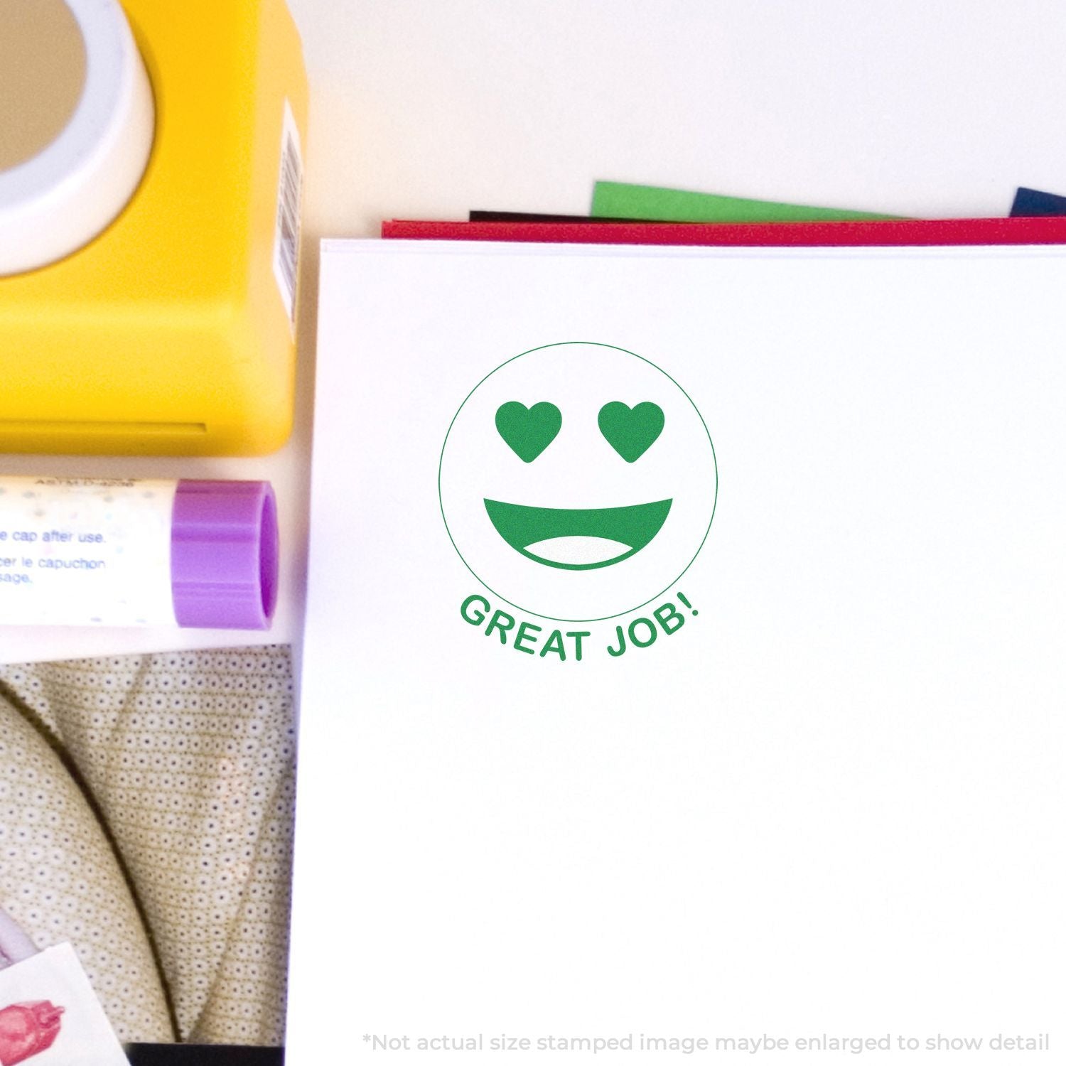 Self Inking Round Great Job Smiley Stamp with heart eyes and Great Job! text stamped on white paper, surrounded by office supplies.