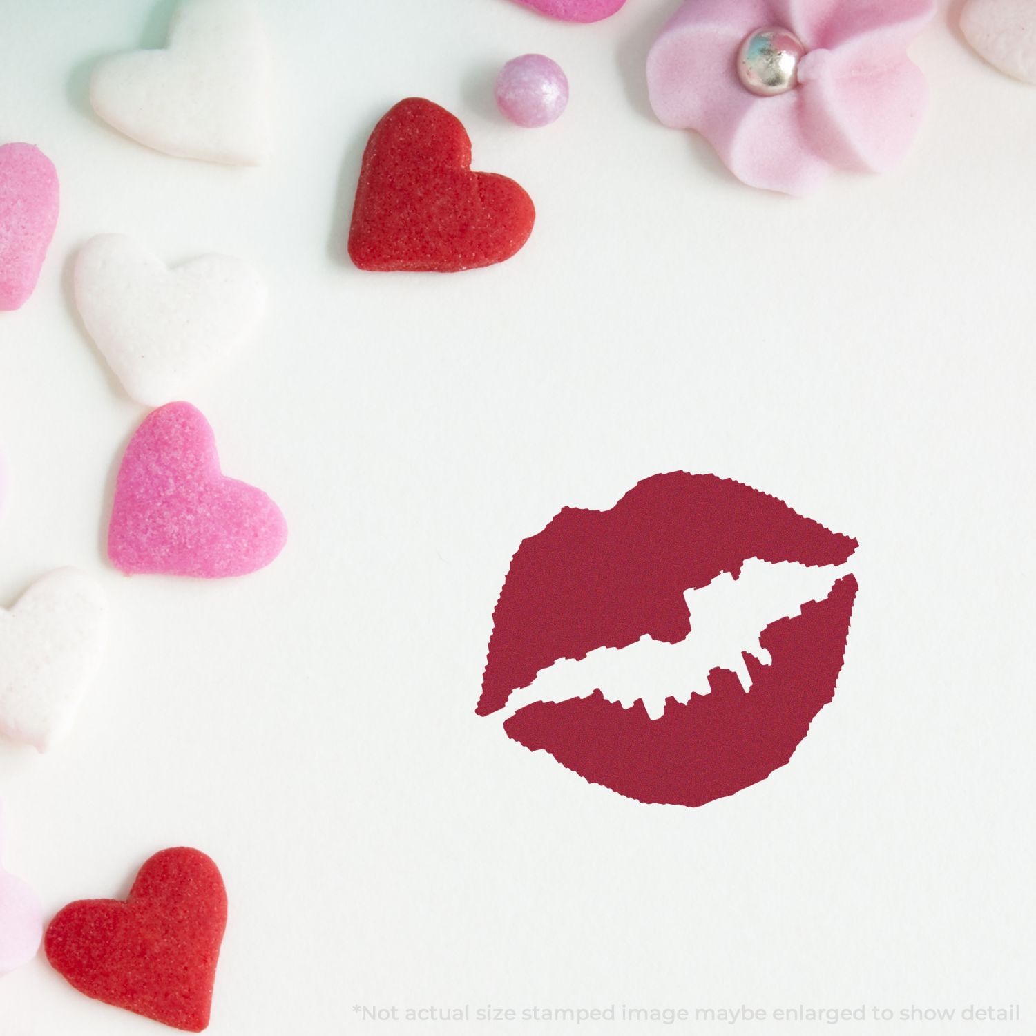 Self Inking Round Kiss Stamp imprint on white paper, surrounded by pink, red, and white heart-shaped decorations and flower embellishments.