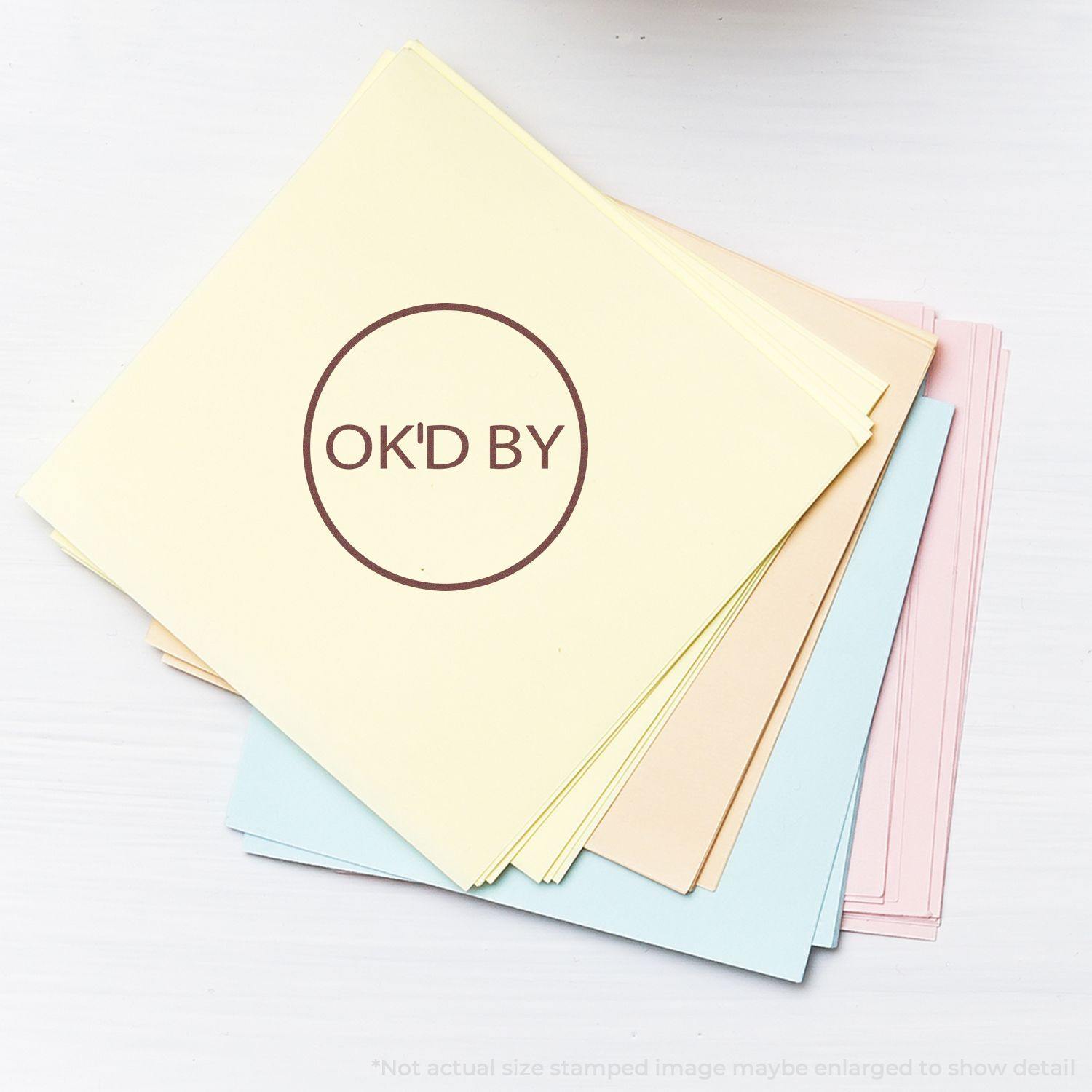 A stack of pastel-colored papers with a Round OK'd By rubber stamp mark in the center of the top sheet.