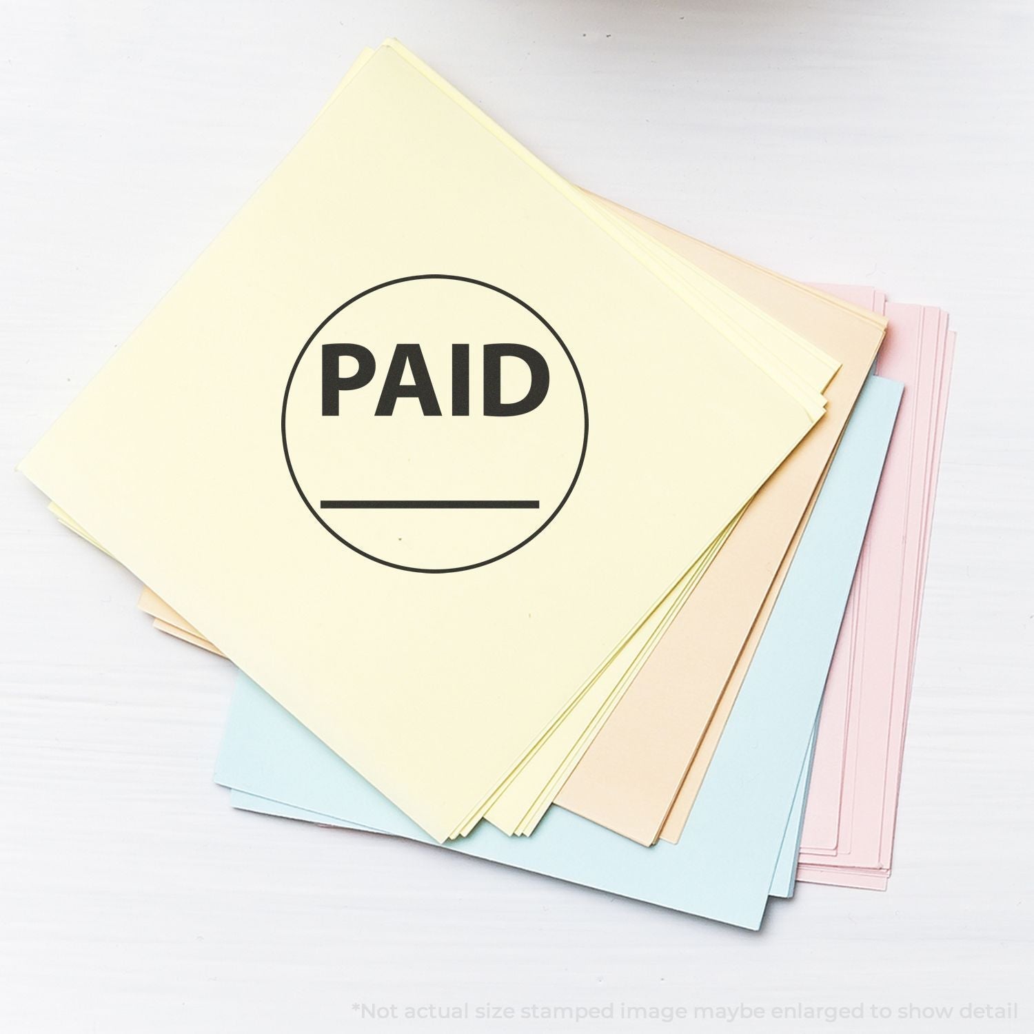 A stack of pastel-colored papers stamped with PAID using the Self Inking Round Paid with Line Stamp.