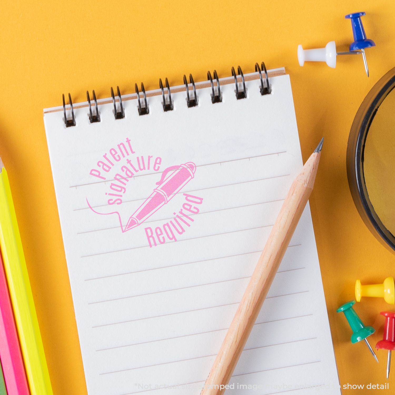 A notepad stamped with the Self Inking Round Parent Signature Required Stamp in pink ink, surrounded by a pencil, push pins, and colorful folders.