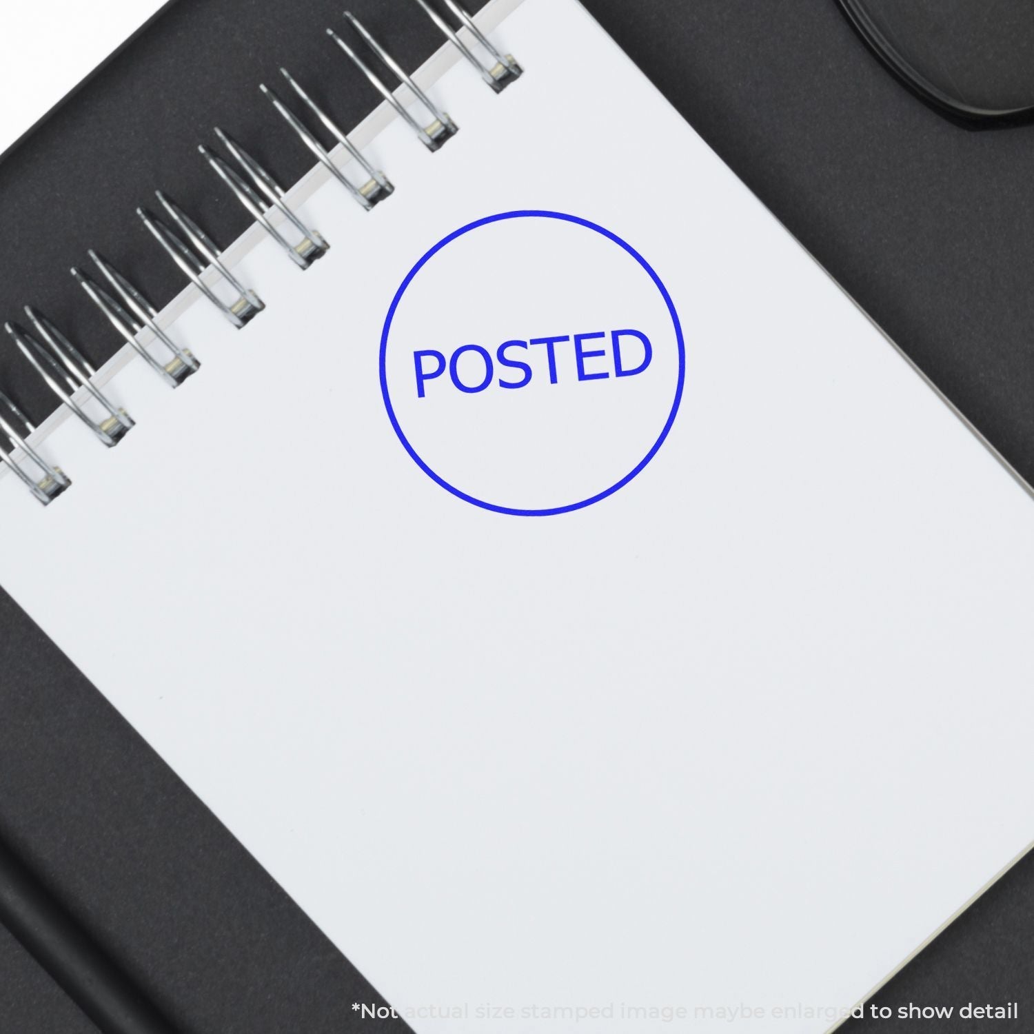 A notebook with a POSTED mark made by the Self Inking Round Posted Stamp in blue ink, placed on a black surface.