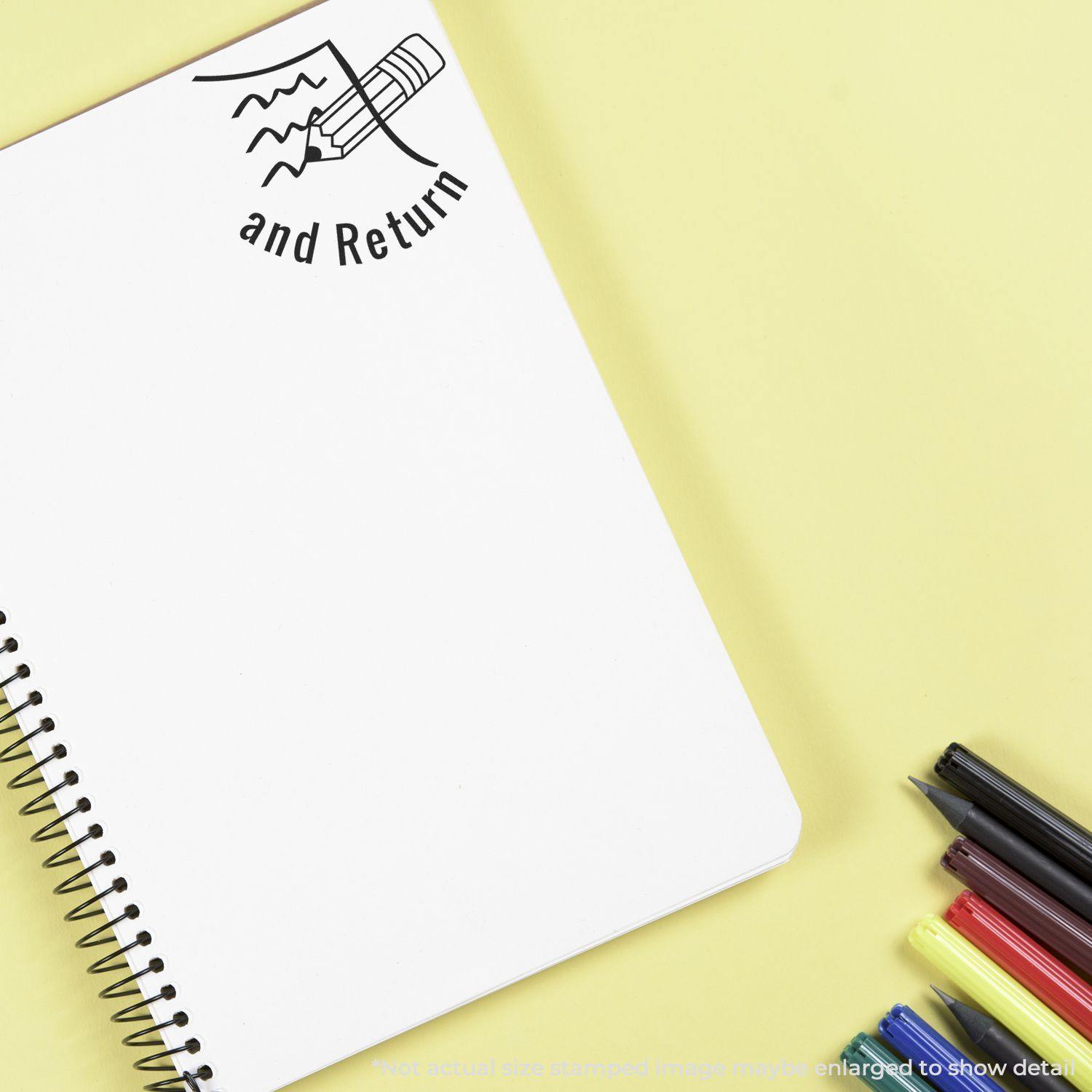 Round Sign and Return rubber stamp on a blank spiral notebook page, with colored pens on a yellow background.