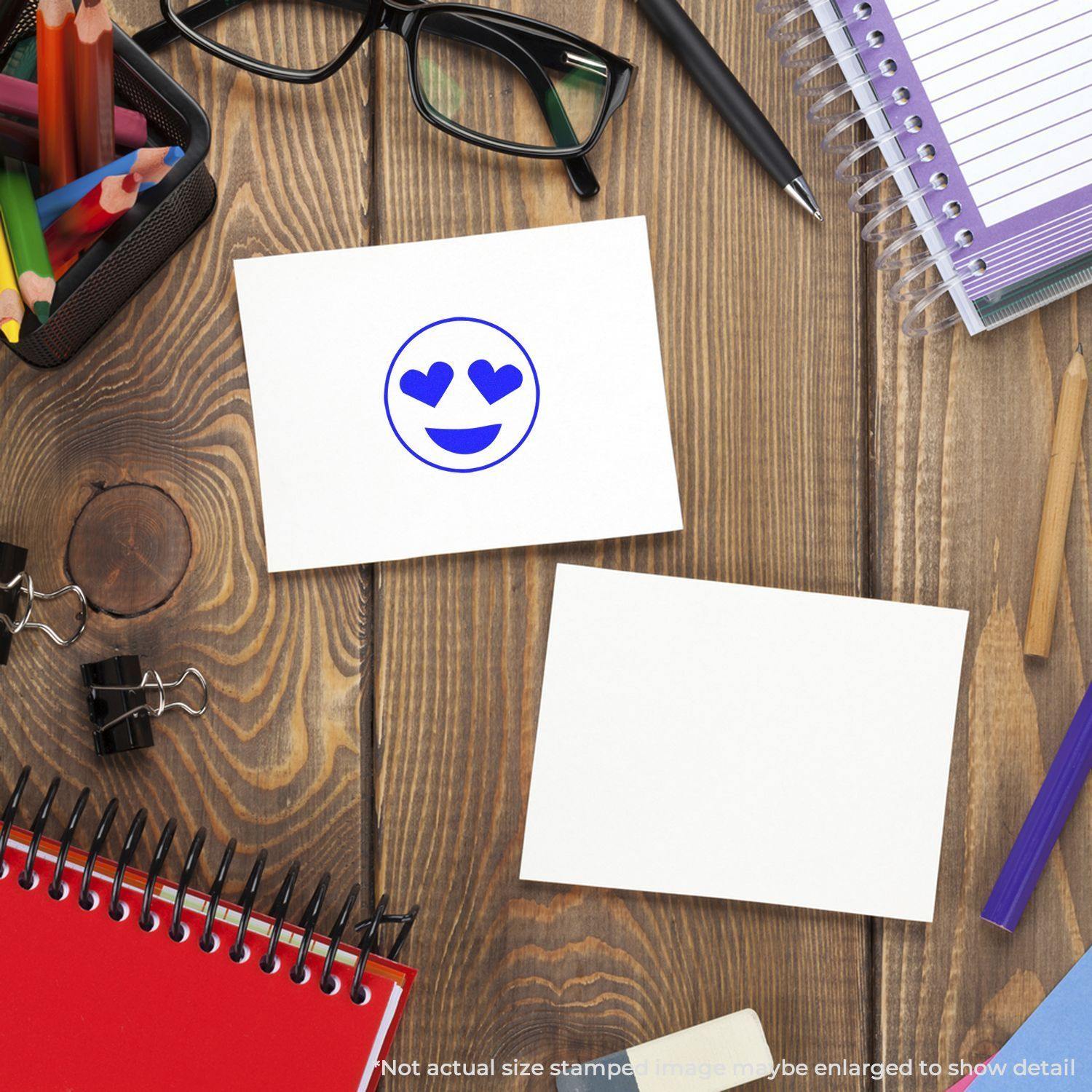 Round Smiley with Hearts Rubber Stamp on a white card, surrounded by office supplies on a wooden desk.