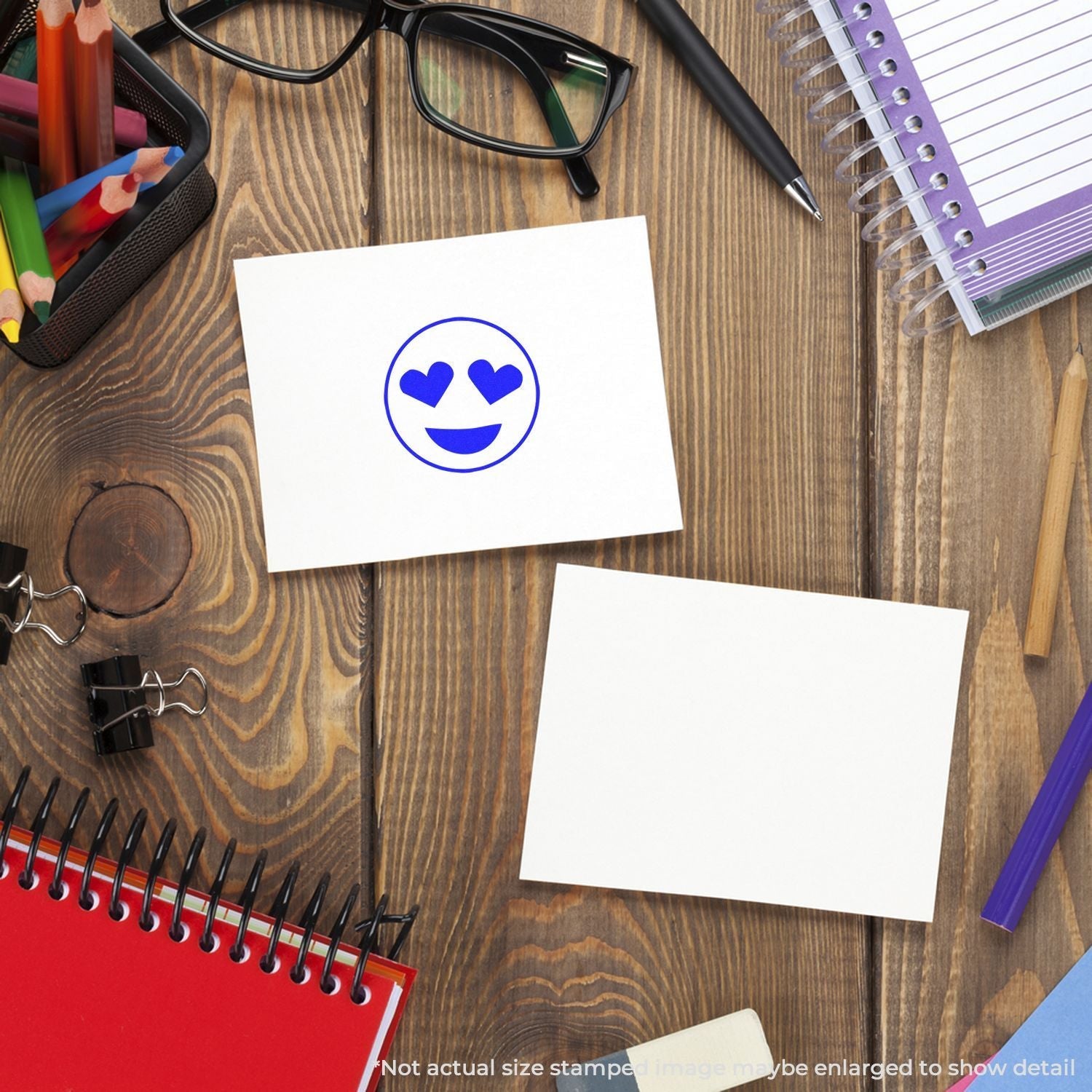 Self Inking Round Smiley with Hearts Stamp on a white card, surrounded by office supplies on a wooden desk.