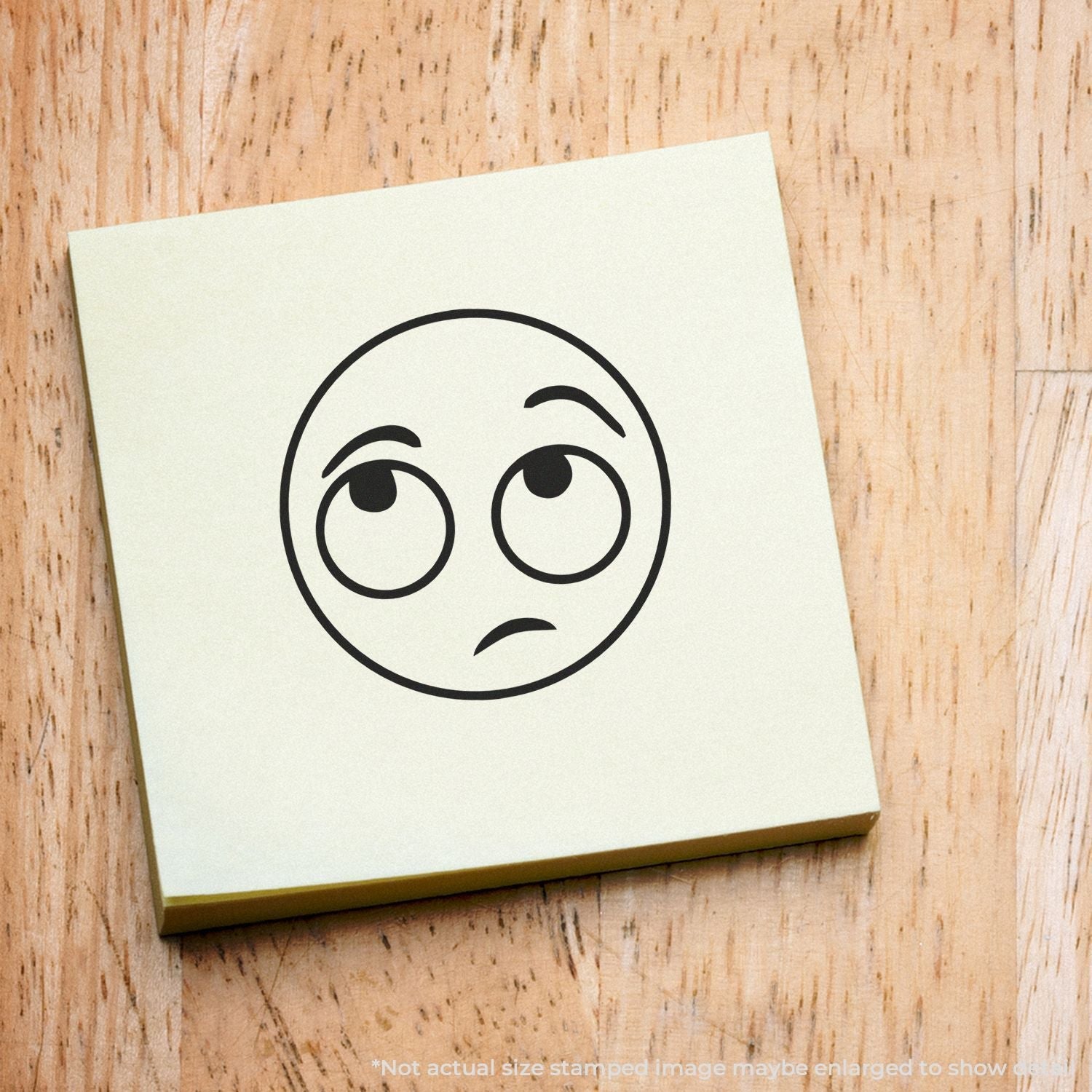 Self Inking Round Whatever Smiley Stamp on a yellow sticky note, displaying a round face with raised eyebrows and a skeptical expression.