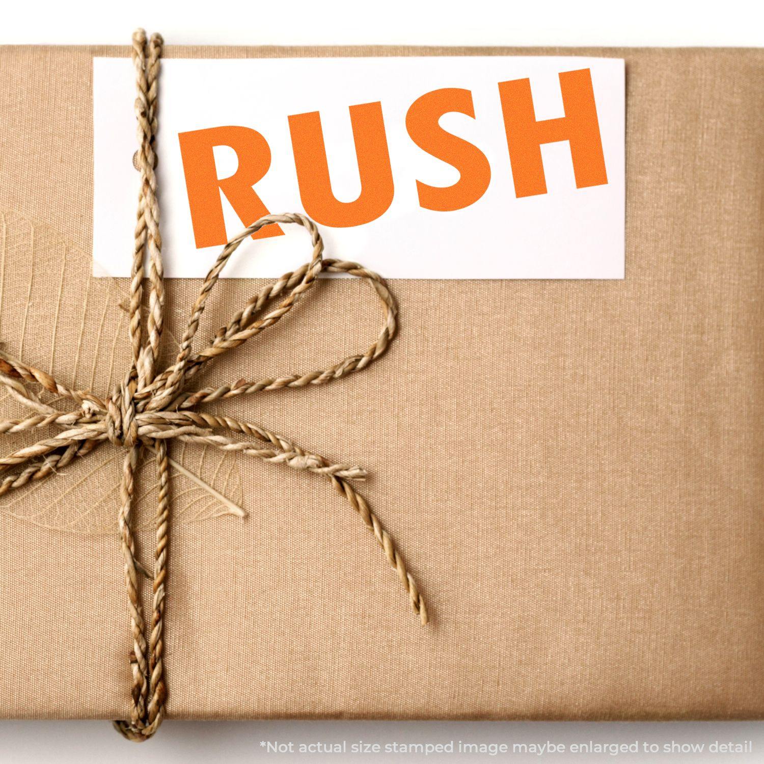 A Large Pre-Inked Rush Stamp is used on a white card attached to a brown wrapped package with a twine bow.