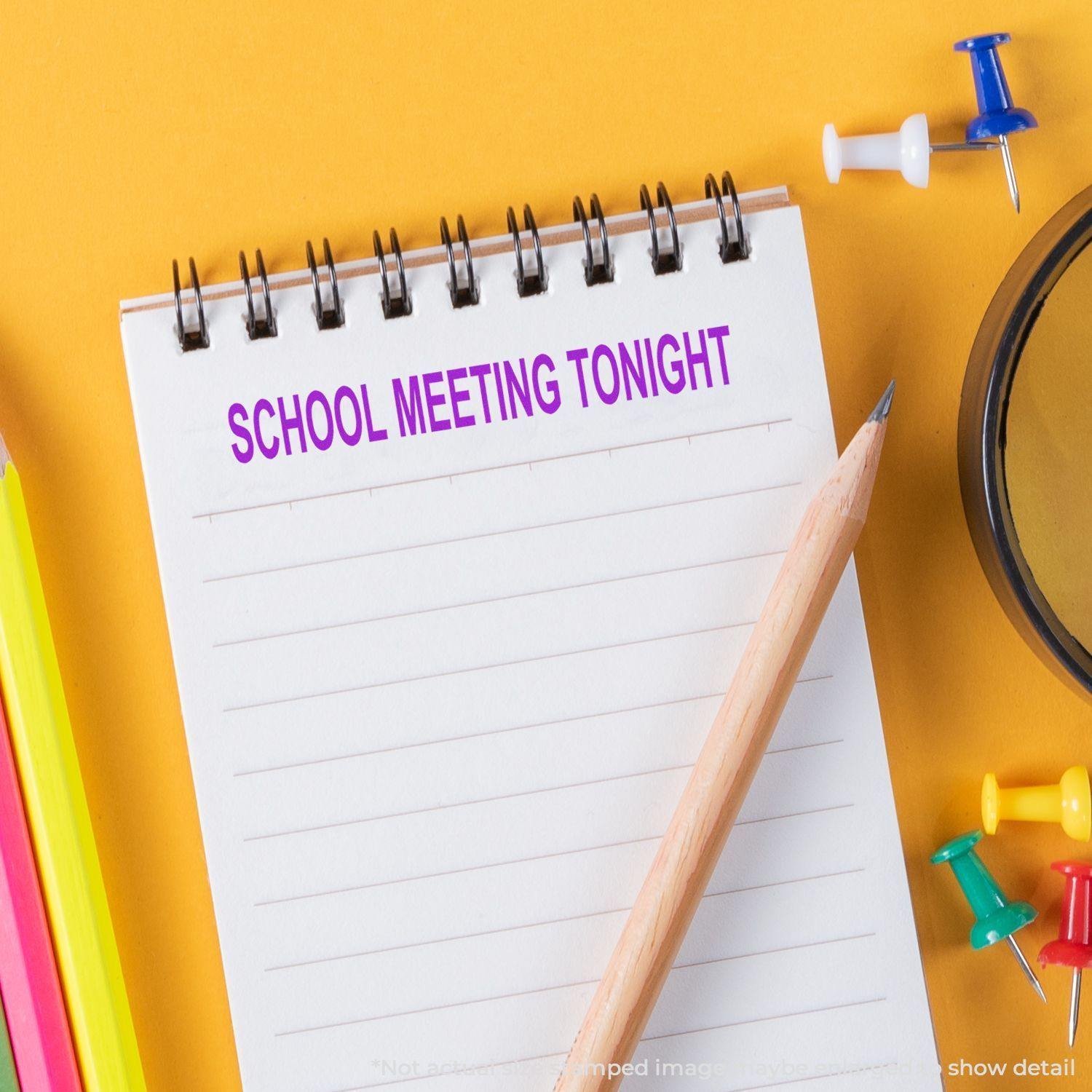 Large Pre-Inked School Meeting Tonight Stamp used on a notepad with colorful push pins, pencils, and a magnifying glass on a yellow background.