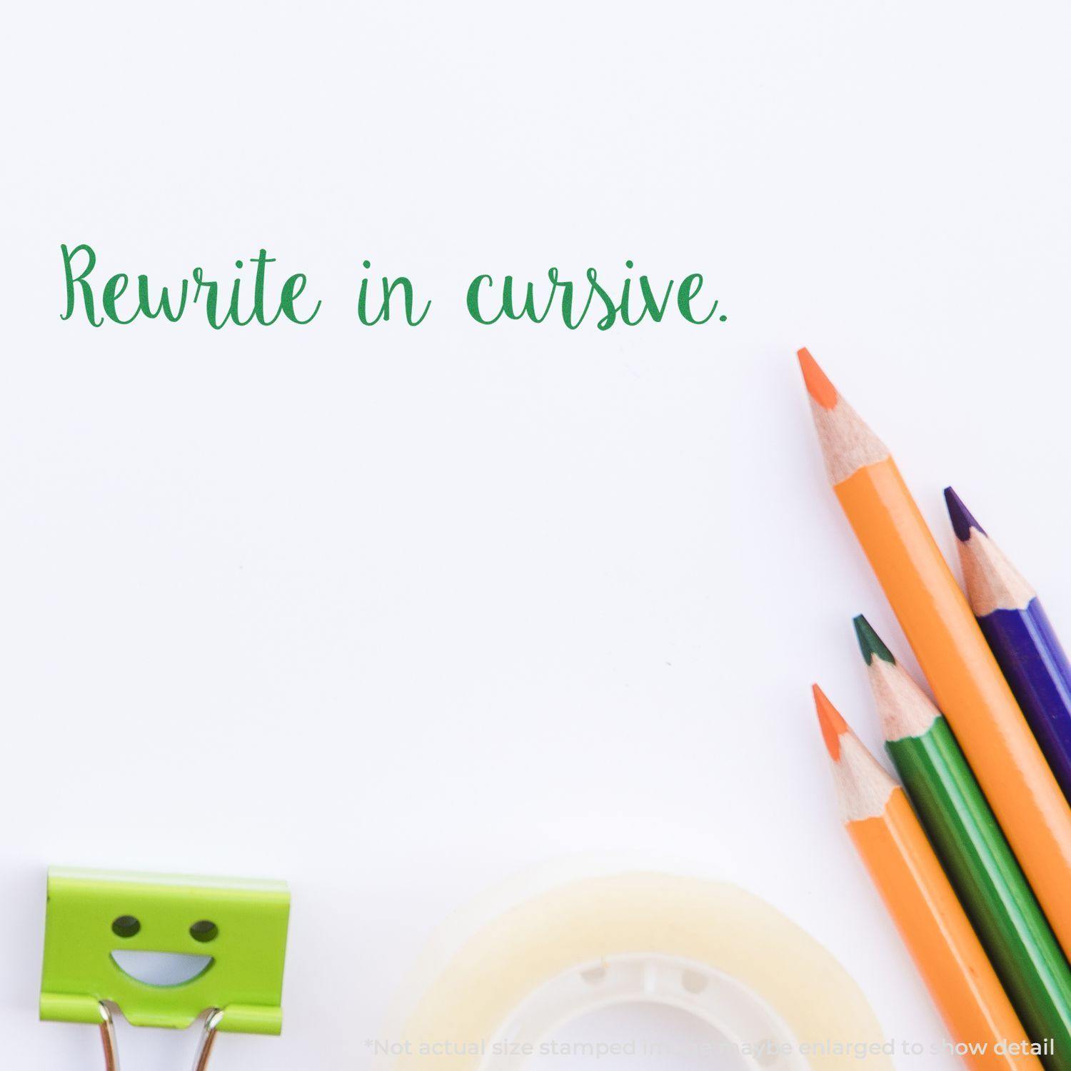 Large Script Rewrite in Cursive Rubber Stamp impression on white paper with colorful pencils, a smiling clip, and tape in the background.