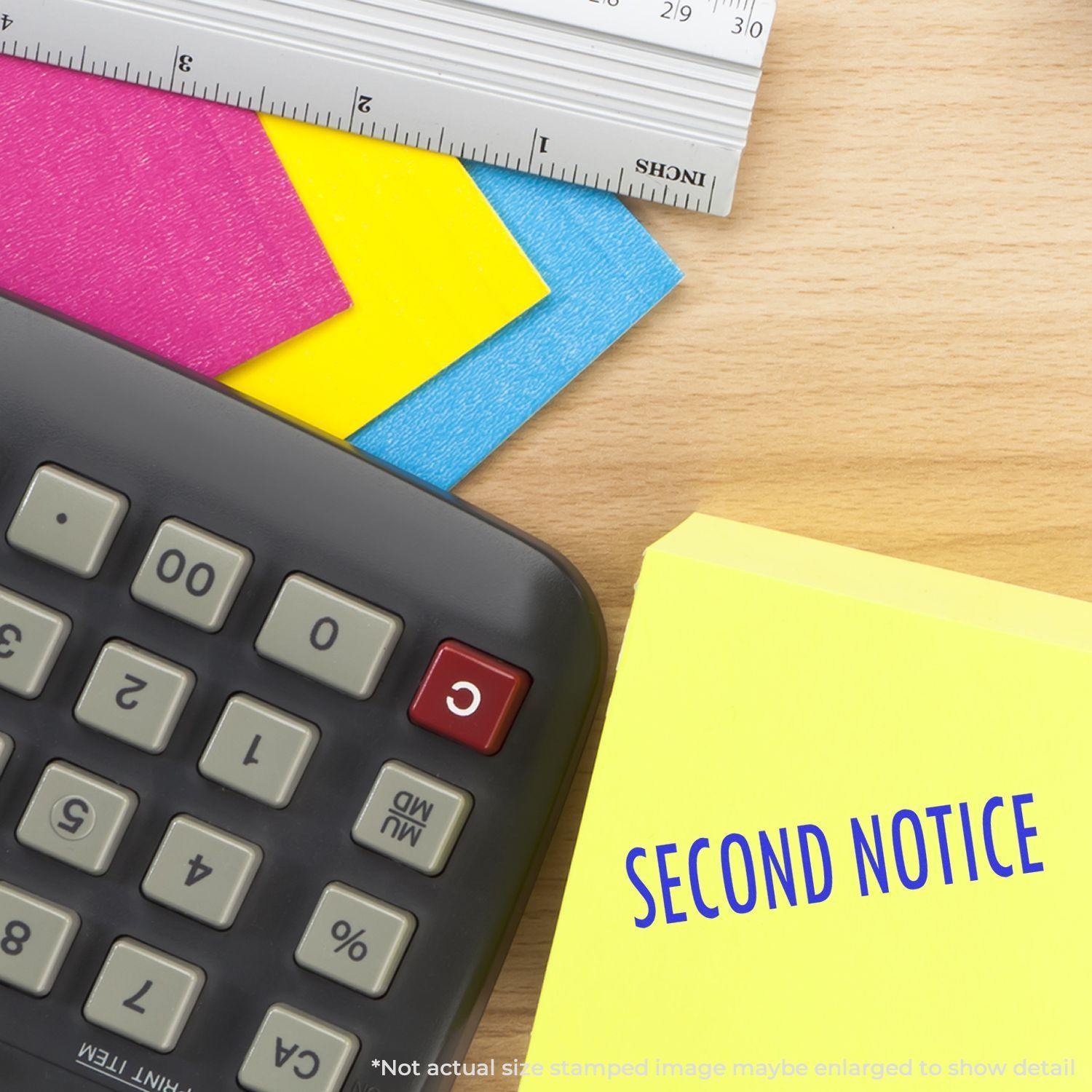 A Large Second Notice Rubber Stamp is shown on a yellow paper next to a calculator, ruler, and colorful index cards on a wooden desk.