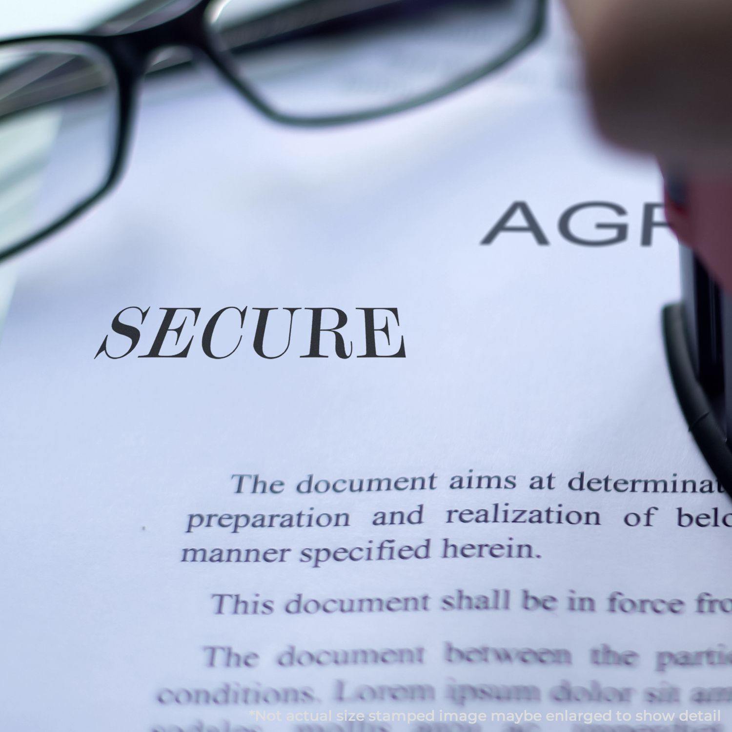 Slim Pre-Inked Secure Stamp in use on a document with the word SECURE stamped, glasses and part of the stamp visible.