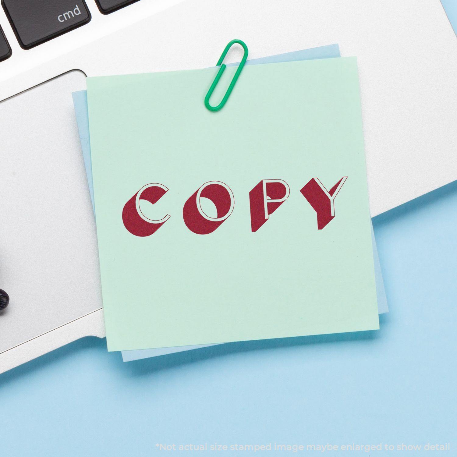 A Self Inking Shadow Copy Stamp imprint on a green sticky note, clipped to a laptop keyboard with a green paperclip.