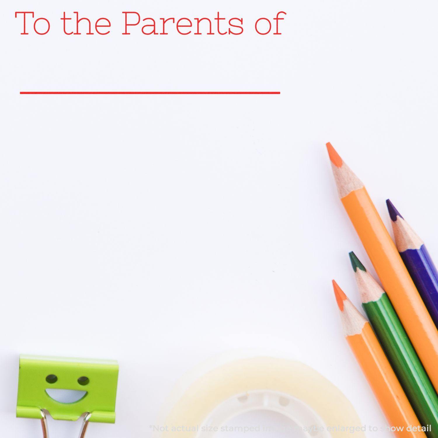 Large Self Inking Skinny To the Parents of Stamp in use, with colorful pencils, a smiley binder clip, and tape on a white background.