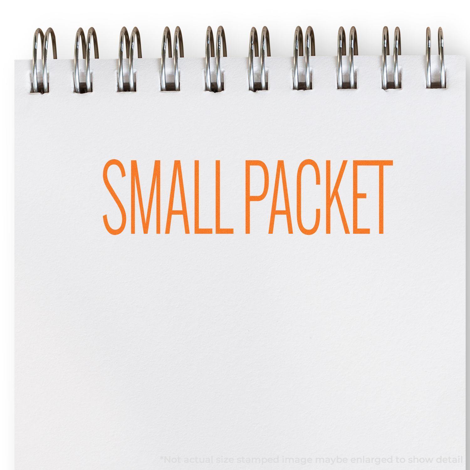 Self Inking Small Packet Stamp imprint on white paper with orange text SMALL PACKET in a spiral notebook.