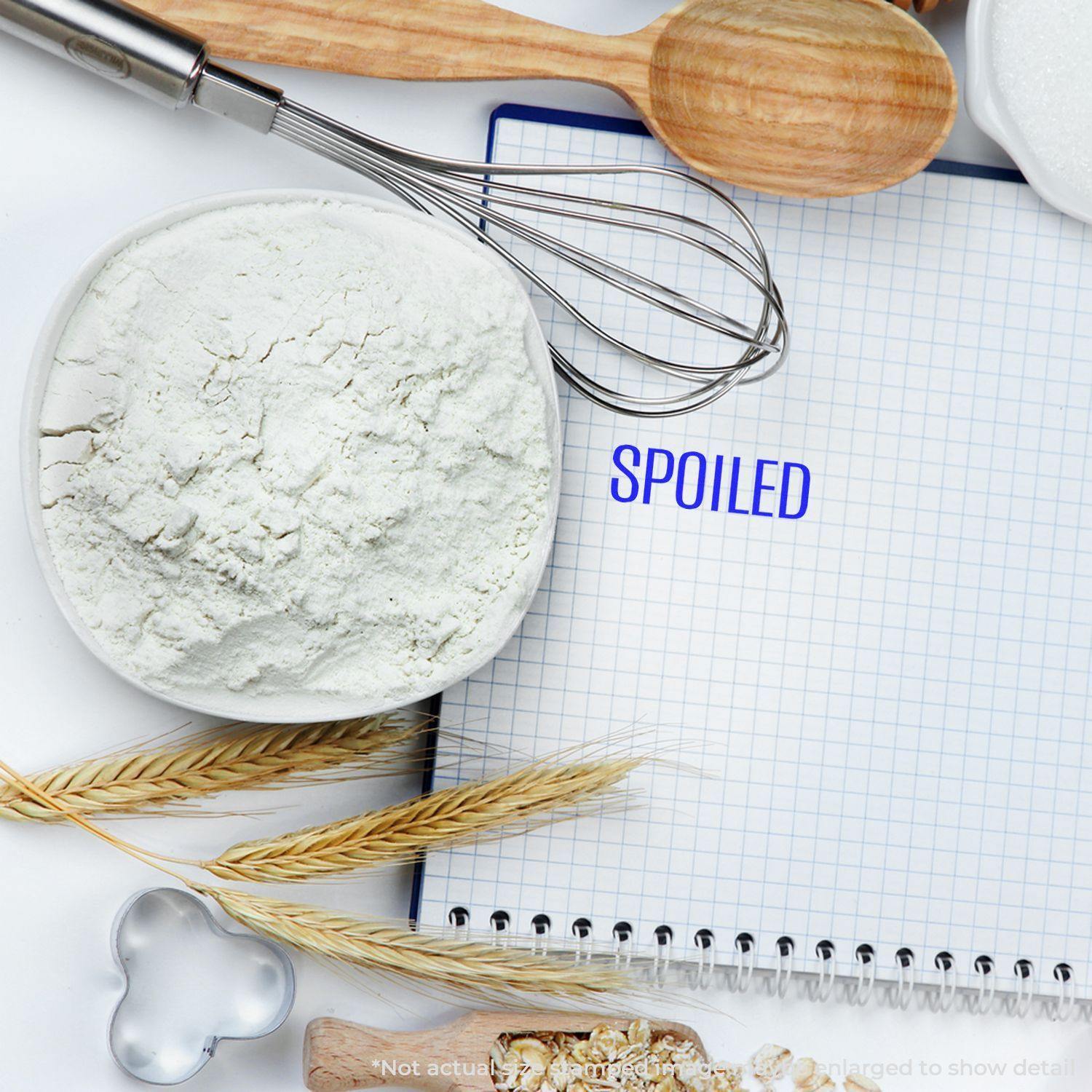 Large Pre-Inked Spoiled Stamp used on a grid notebook, surrounded by baking ingredients and utensils.