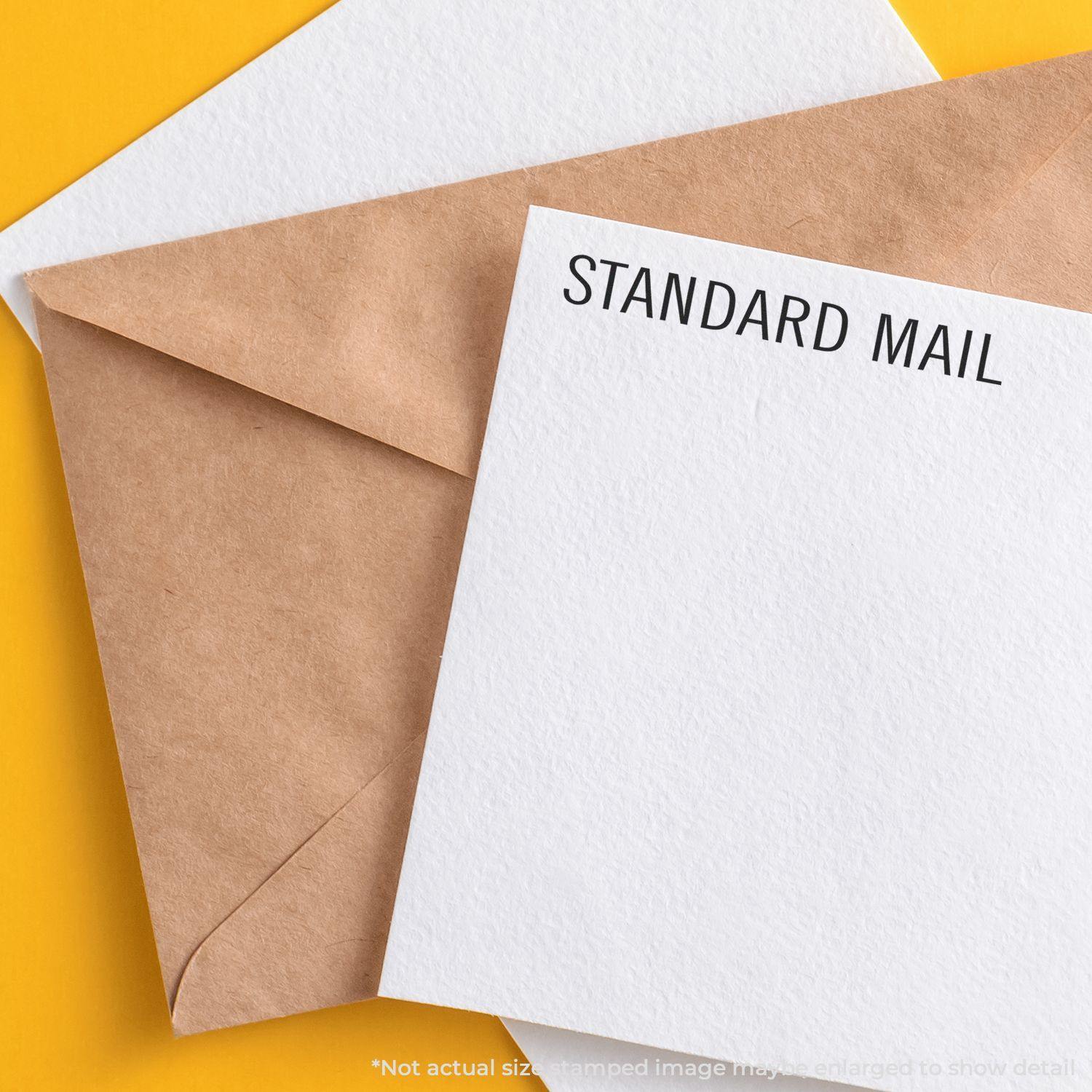 Self Inking Standard Mail Stamp used on a white envelope, placed next to a brown envelope on a yellow background.