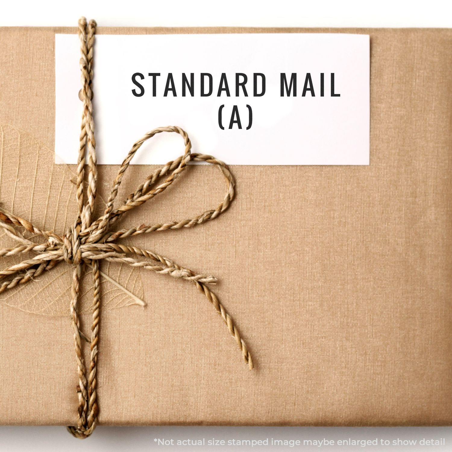 A self-inking stamp with a stamped image showing how the text "STANDARD MAIL (A)" in a large font is displayed by it after stamping.