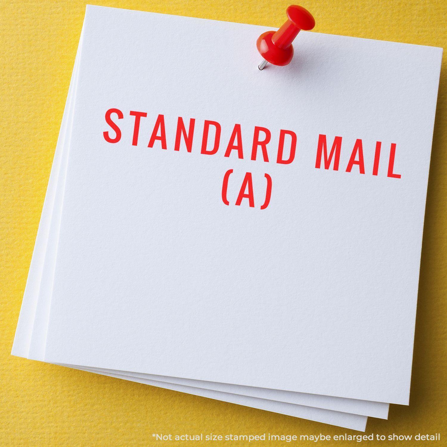 Large Pre-Inked Standard Mail (A) Stamp in red ink on white paper, pinned to a yellow background.