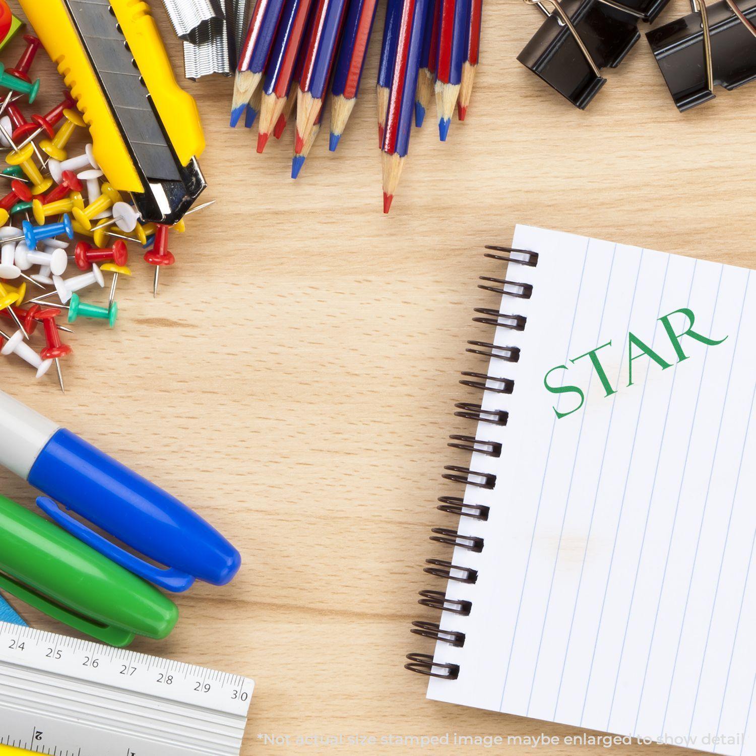 Desk with office supplies, including a notebook stamped with a large star rubber stamp, surrounded by pens, push pins, and clips.