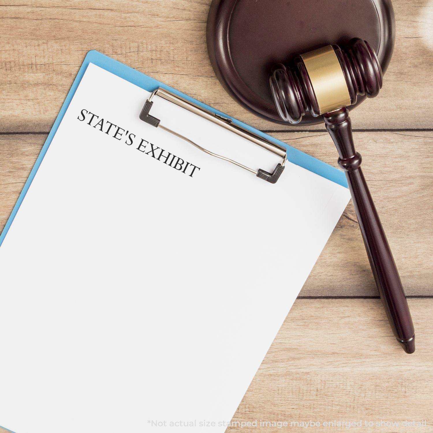 Large States Exhibit rubber stamp on a clipboard with a gavel beside it on a wooden table.